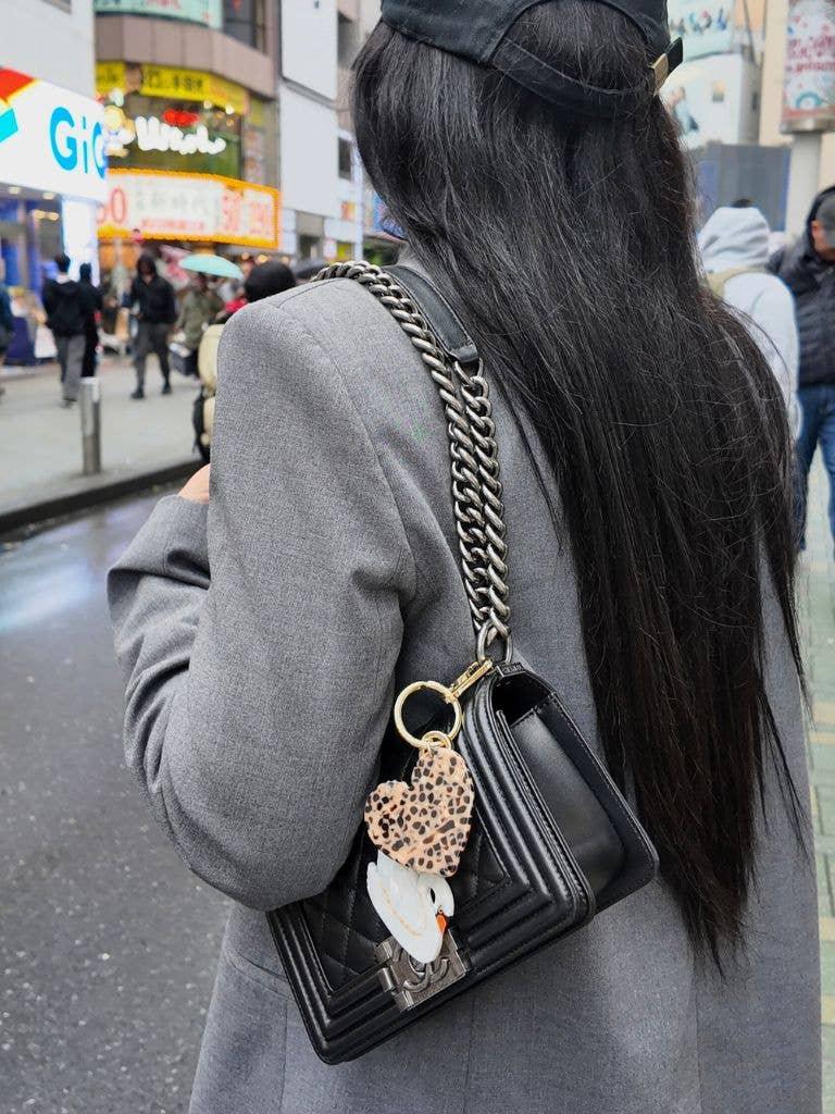 Chanel Boy black leather chain bag with leopard heart keychain and swan charm on street