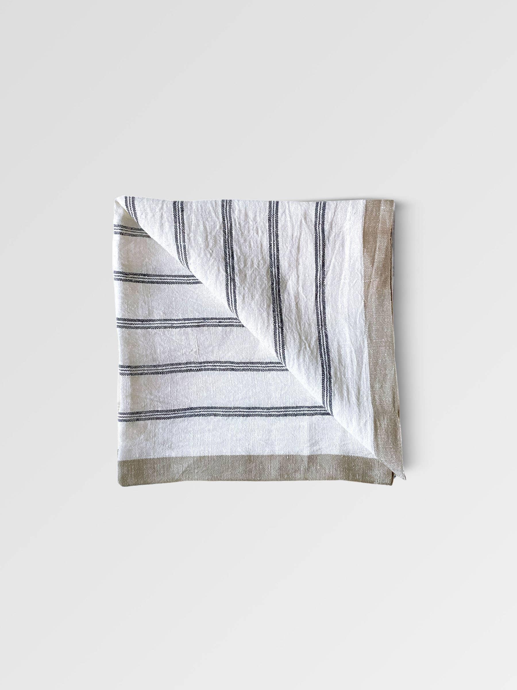Tensira linen napkin, white with black stripes, premium folded textile on plain background
