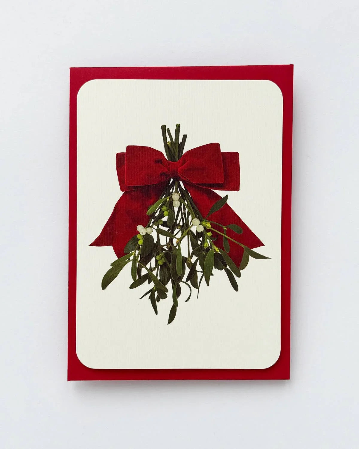 Moglea holiday card with red velvet bow and green mistletoe on premium white card stock