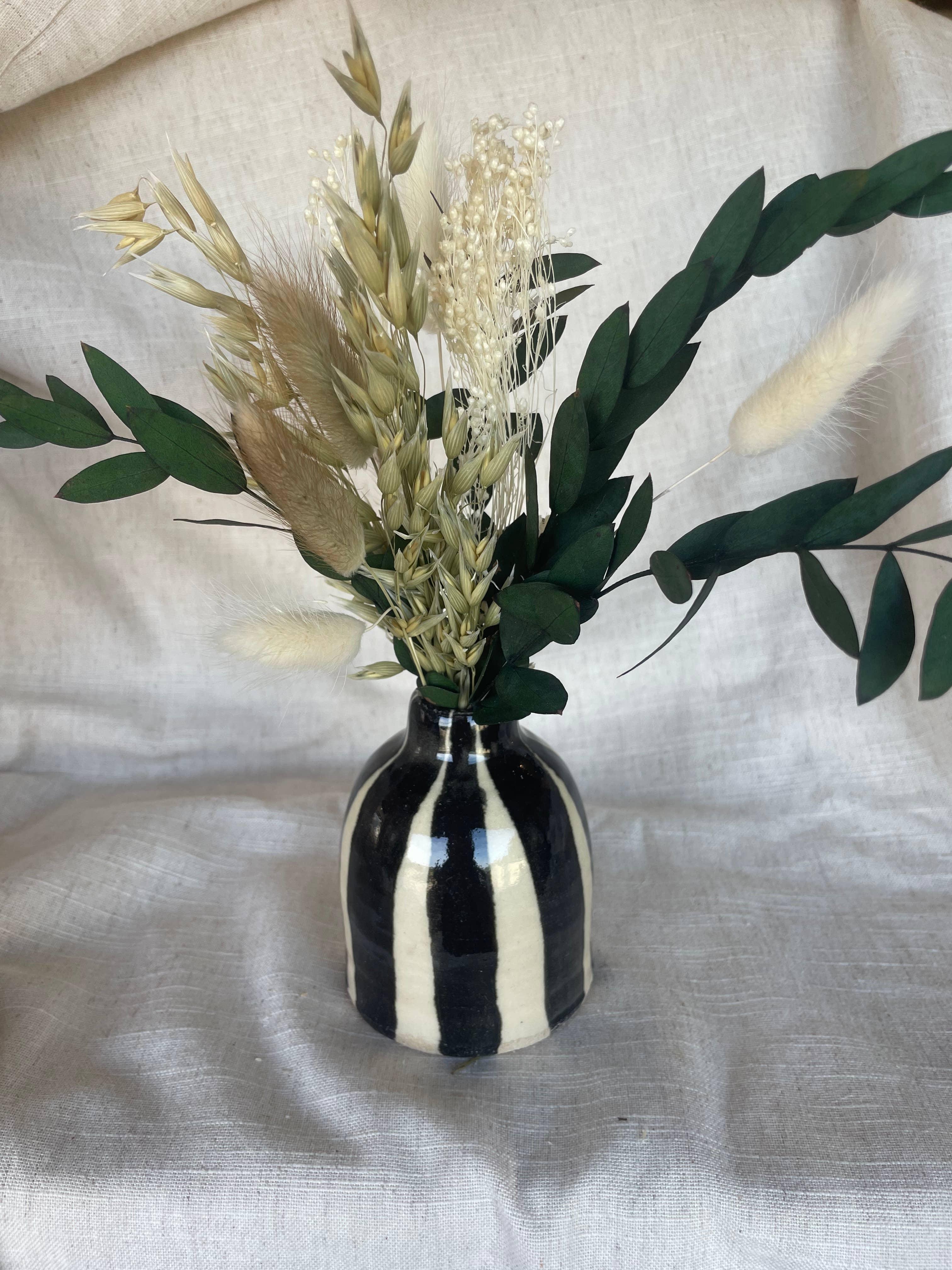 BKIND ceramic striped vase with dried flowers, black and cream, on neutral fabric