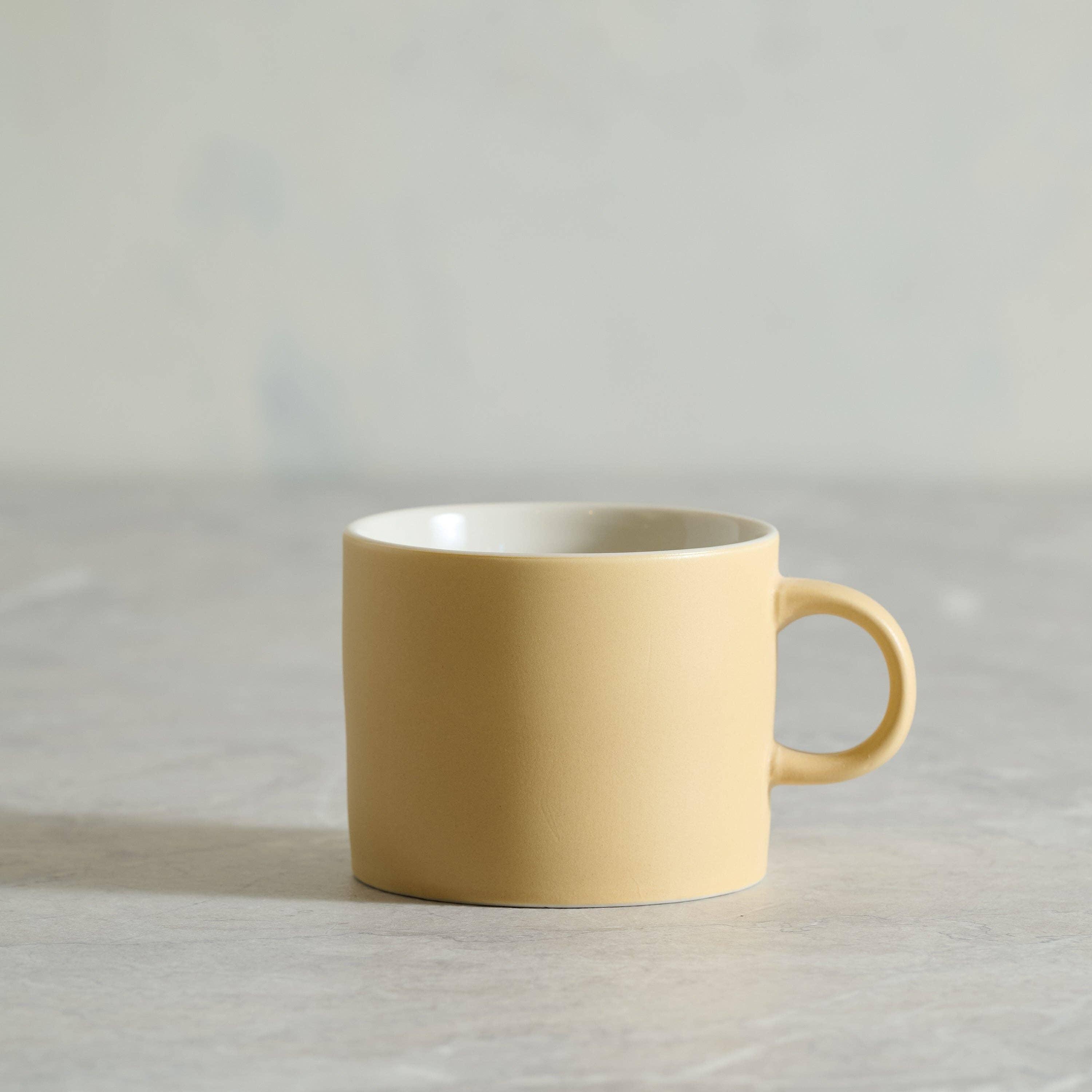 Kinto yellow ceramic mug with matte finish on neutral tabletop
