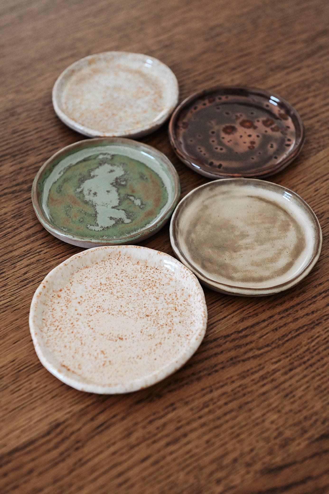 Mikamino handmade ceramic plates, assorted earthy tones, stoneware, on wooden table