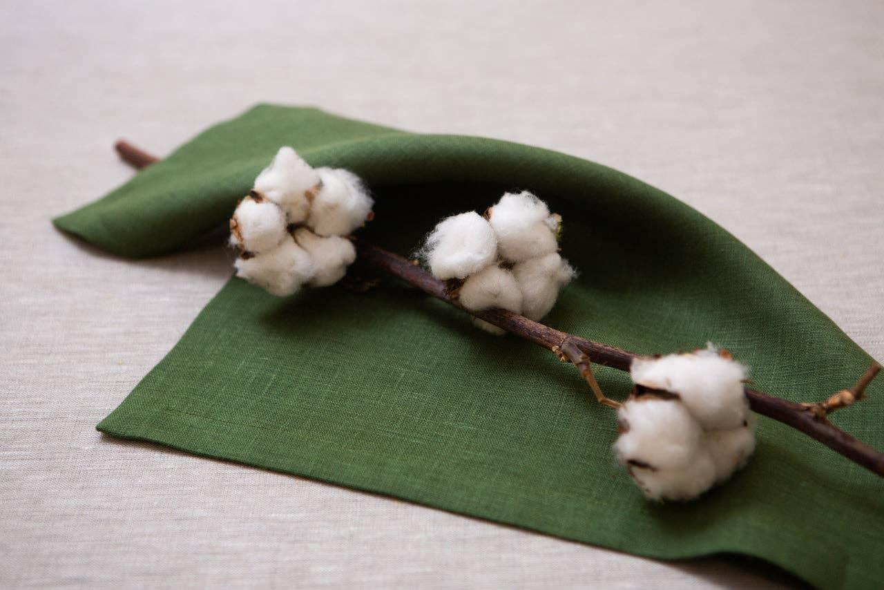 Green linen napkin with cotton branch on beige tablecloth
