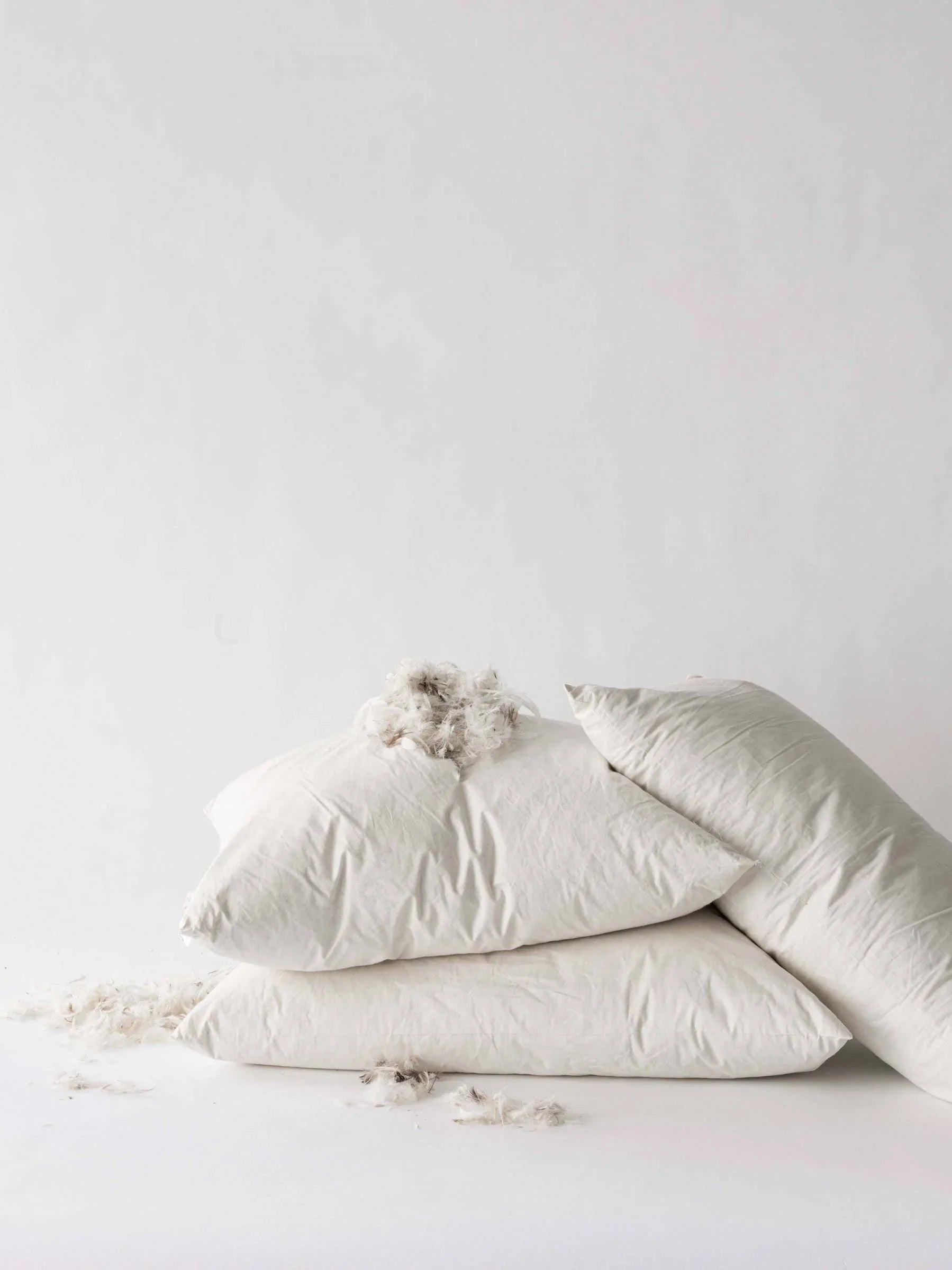 Fluff Co premium white pillows with down filling stacked on white surface