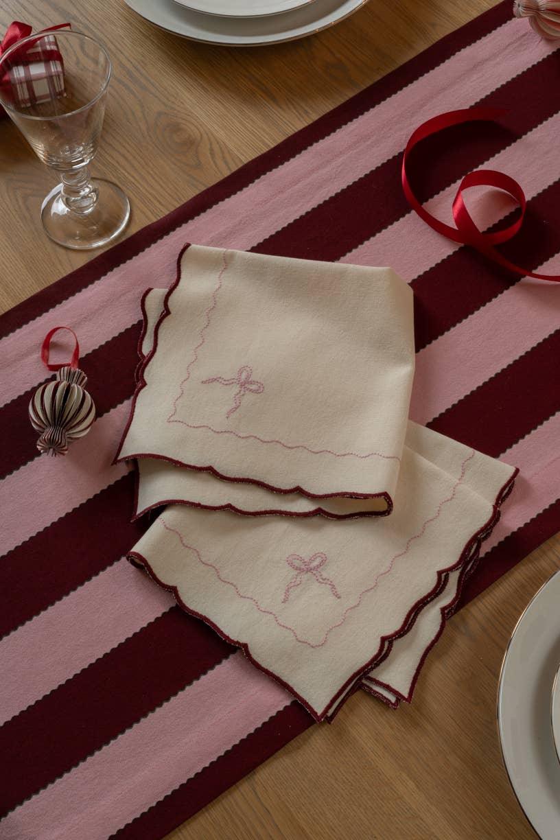 Mrs. Alice embroidered cotton napkins in cream with pink and burgundy trim on striped table runner