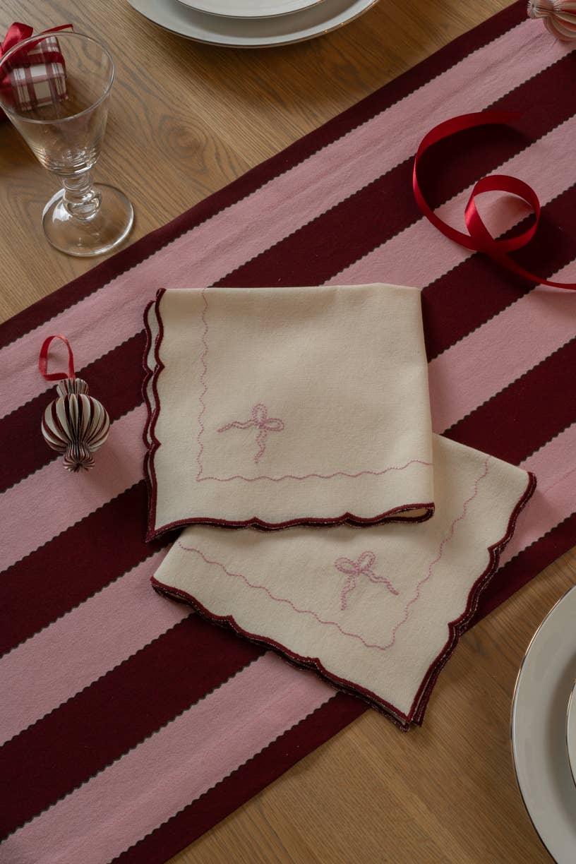 Mrs. Alice linen napkins, ivory with red embroidered edges, on a pink and burgundy striped runner