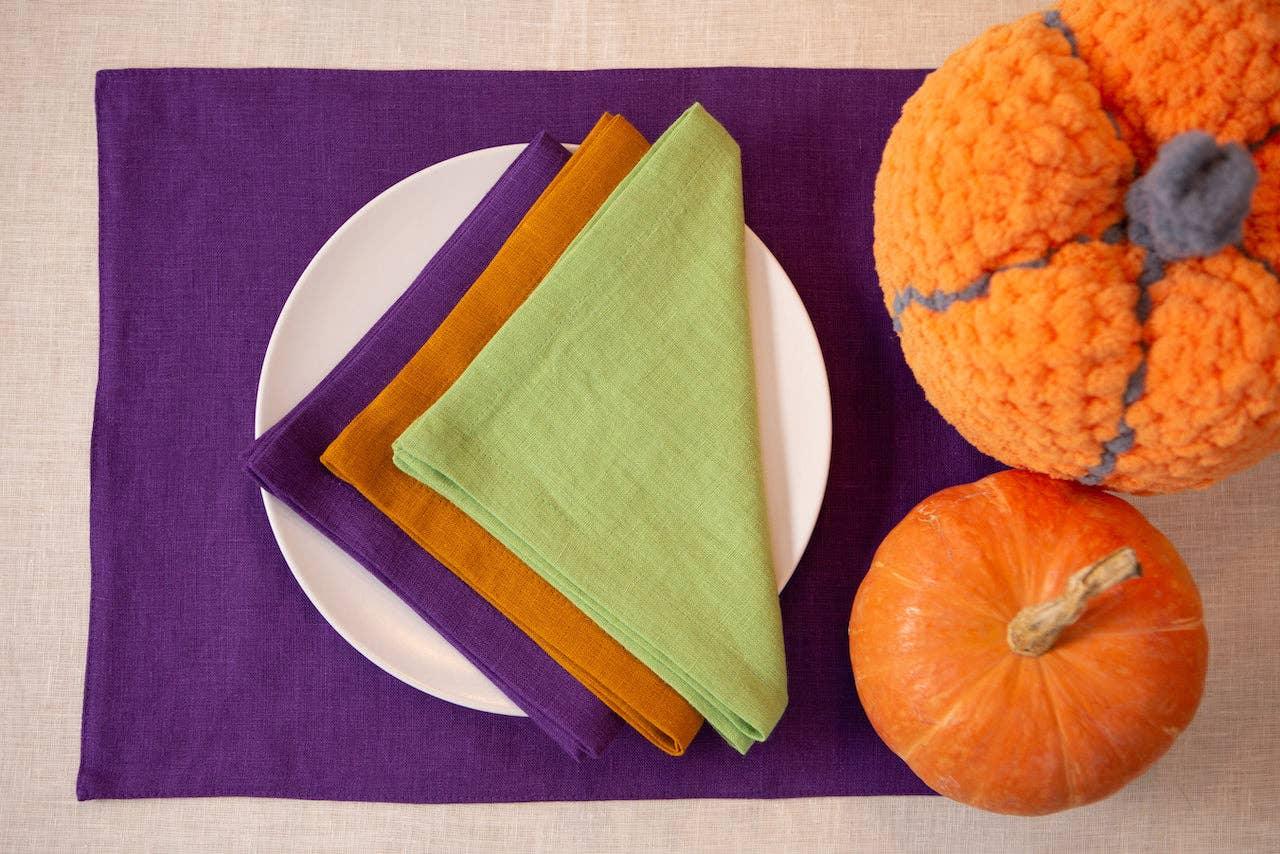 Linen Tales linen napkins in green, gold, and purple on white plate with pumpkins, purple placemat