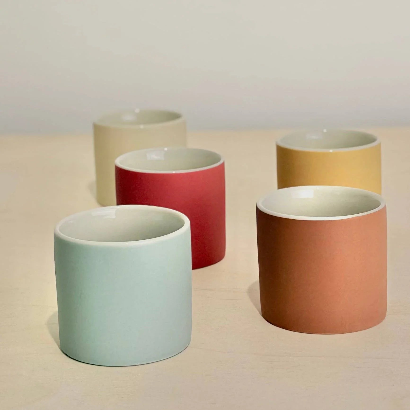 Kana London ceramic cups set in pastel blue, red, cream, yellow and terracotta tones