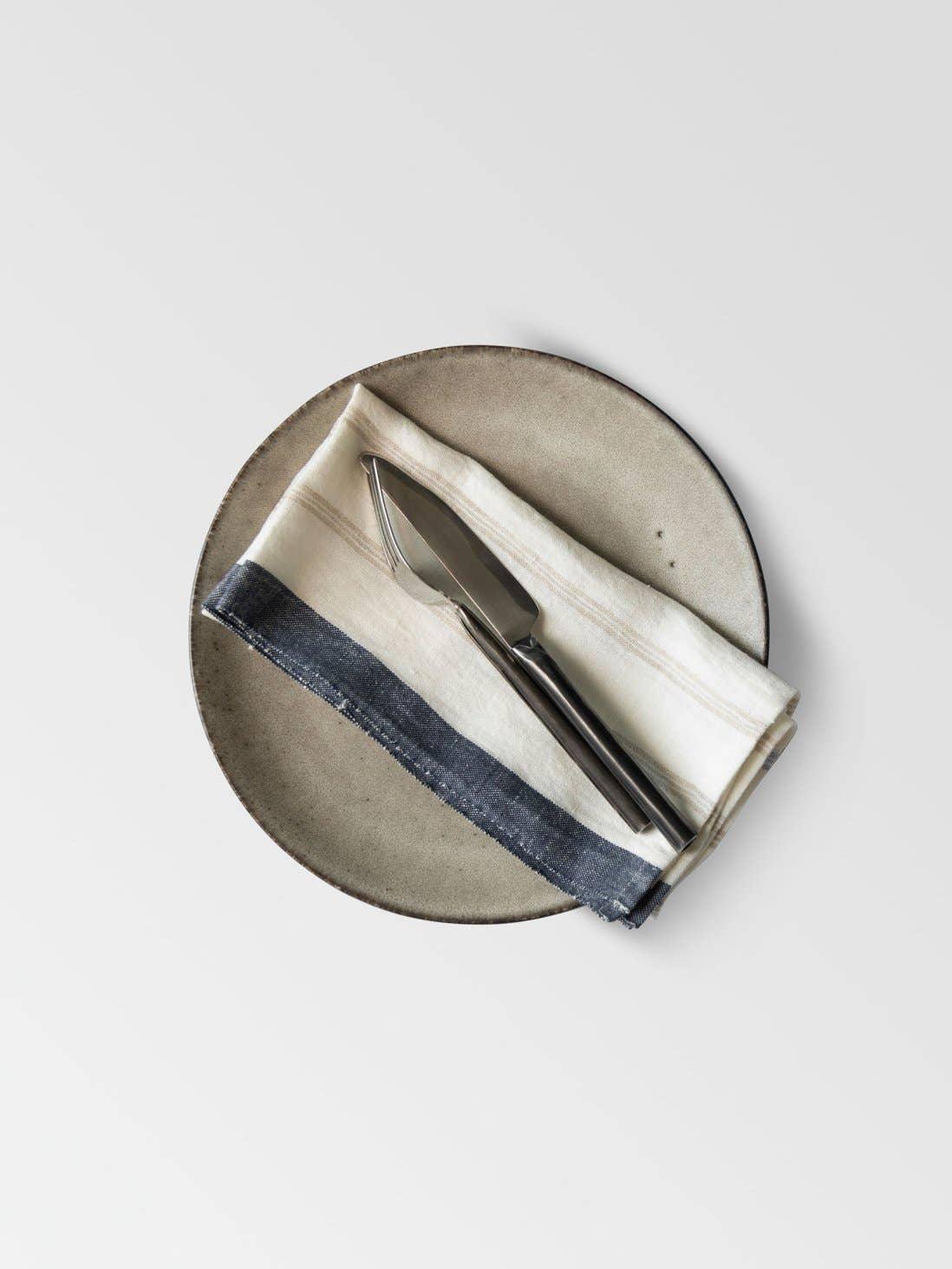 Iris Hantverk stoneware plate with linen napkin and stainless steel cheese knife