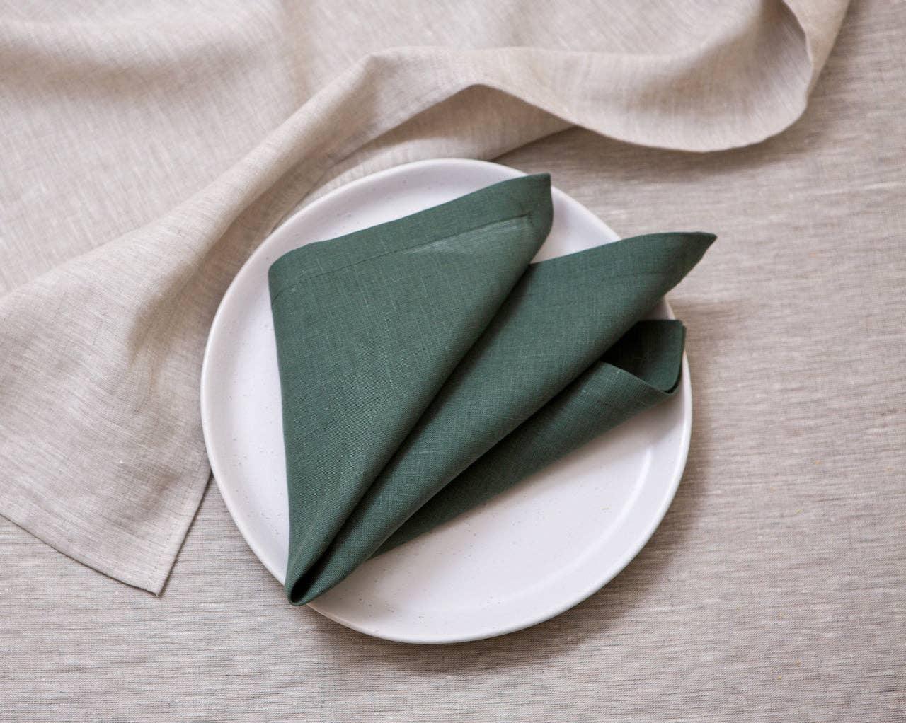MagicLinen green linen napkin on white plate, neutral linen tablecloth background