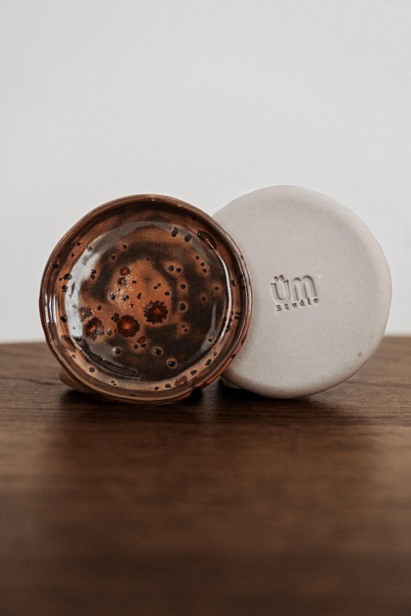 Üm Studio ceramic dish set, brown glazed and matte white, on wooden surface.
