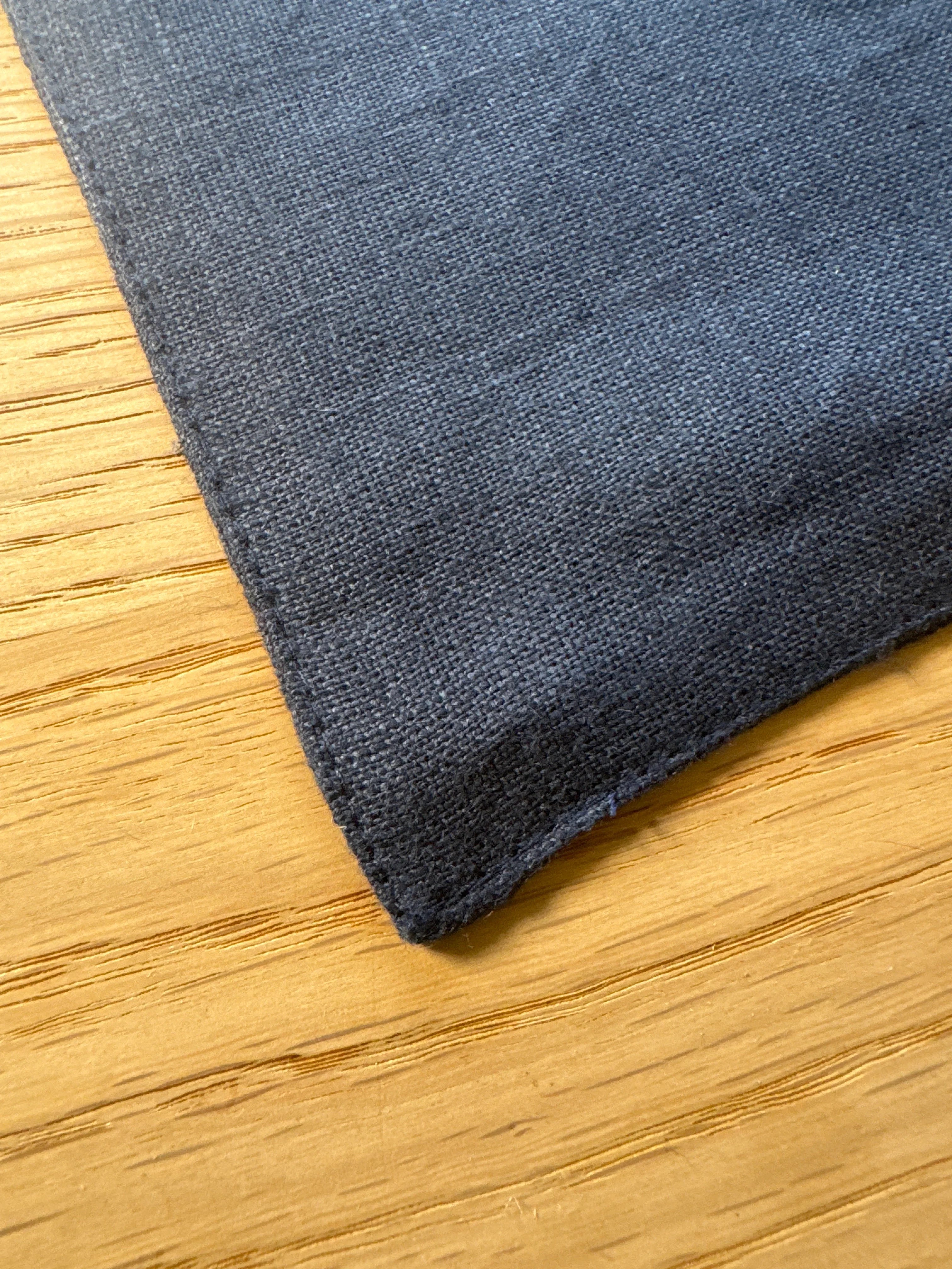 Blue linen napkin corner on wooden table, premium woven fabric texture