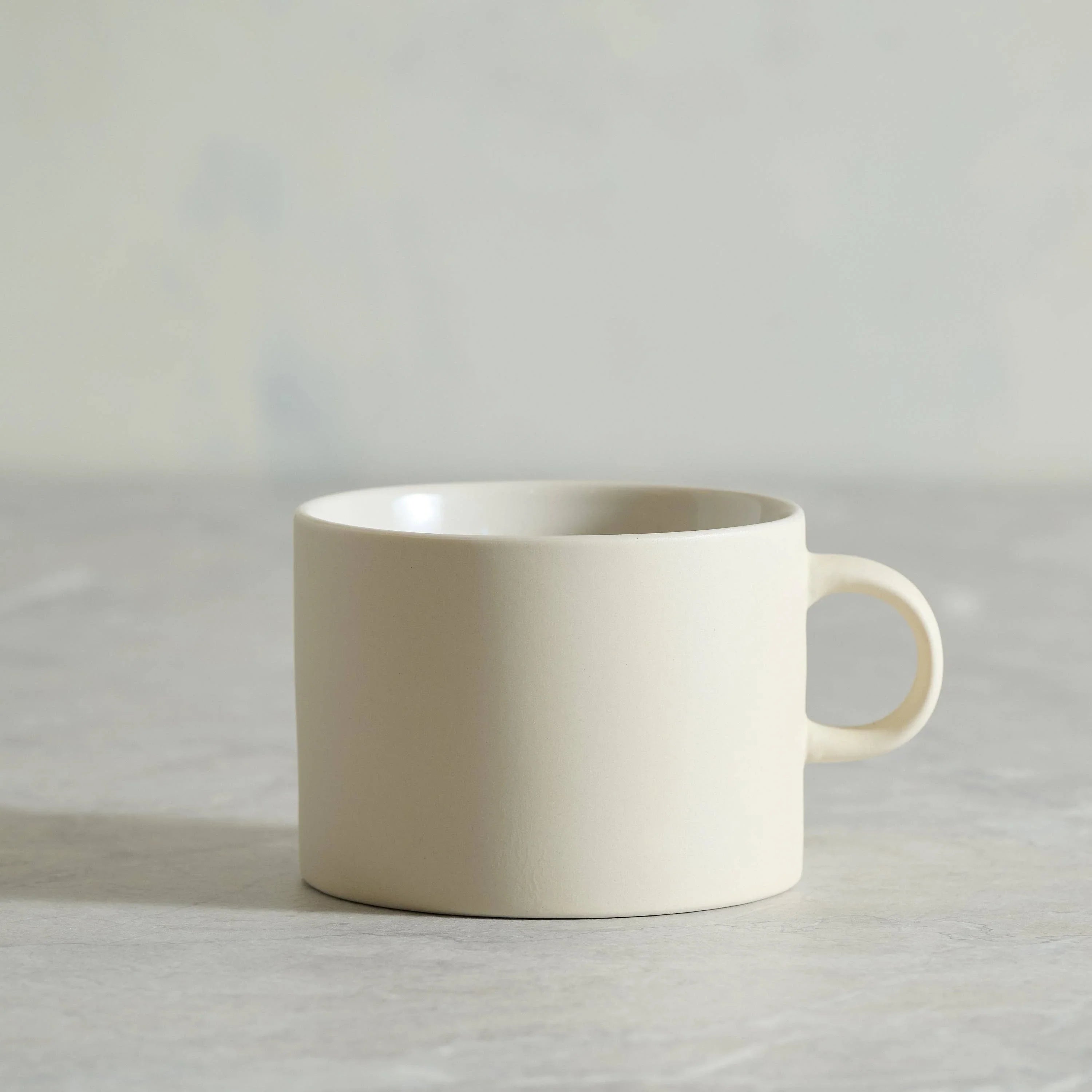 HASAMI PORCELAIN cream ceramic mug with handle on light stone surface