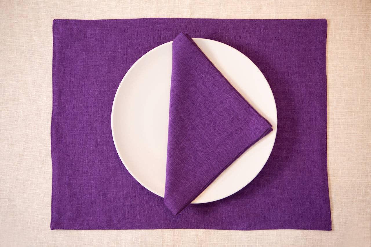 Linen Tales purple linen placemat and napkin set with white ceramic plate on beige table