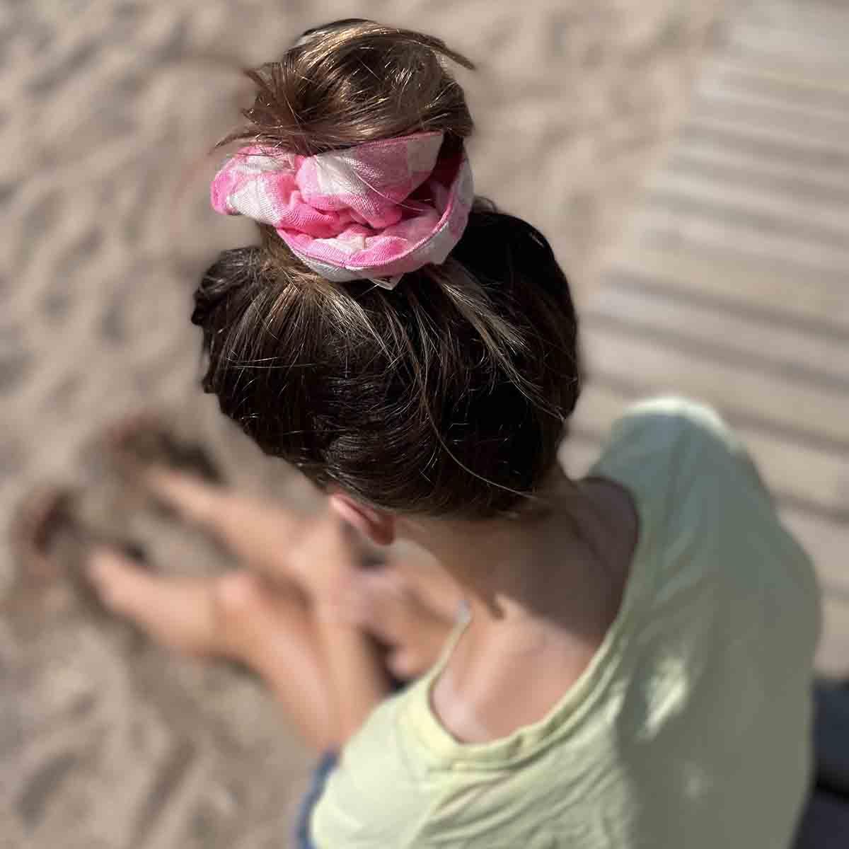 ShikShok pink plaid cotton hair scrunchie in top knot, woman sitting on sandy beach