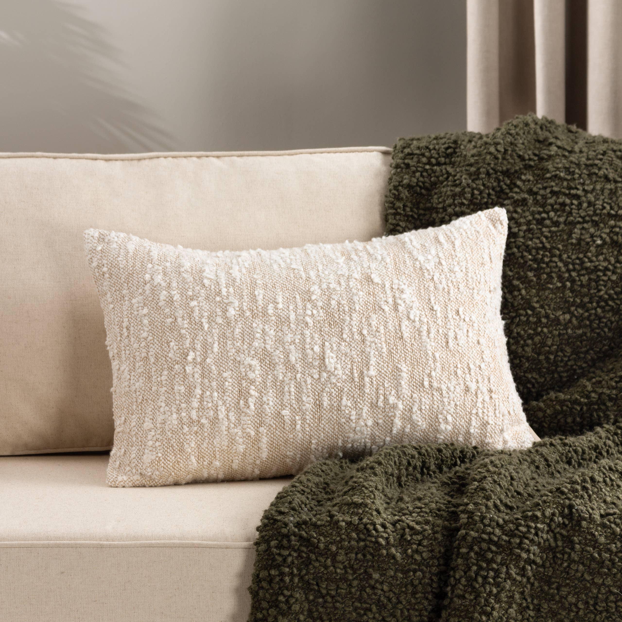 Indaba textured cream throw pillow, woven fabric, on beige sofa with green knit blanket