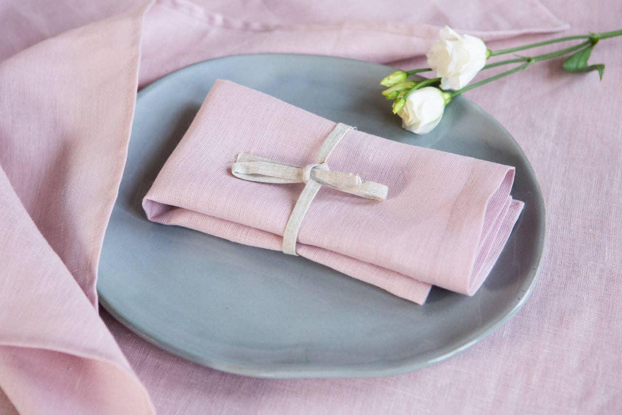 Linen Tales pink linen napkin on grey plate with ribbon and white flower, elegant table setting