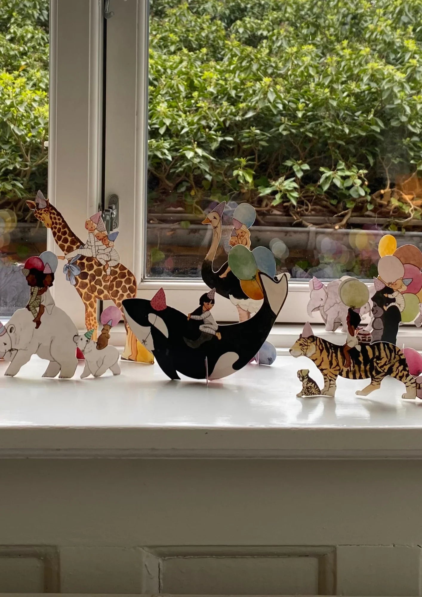 Meri Meri paper animal parade decorations with children, pastel balloons, and party hats