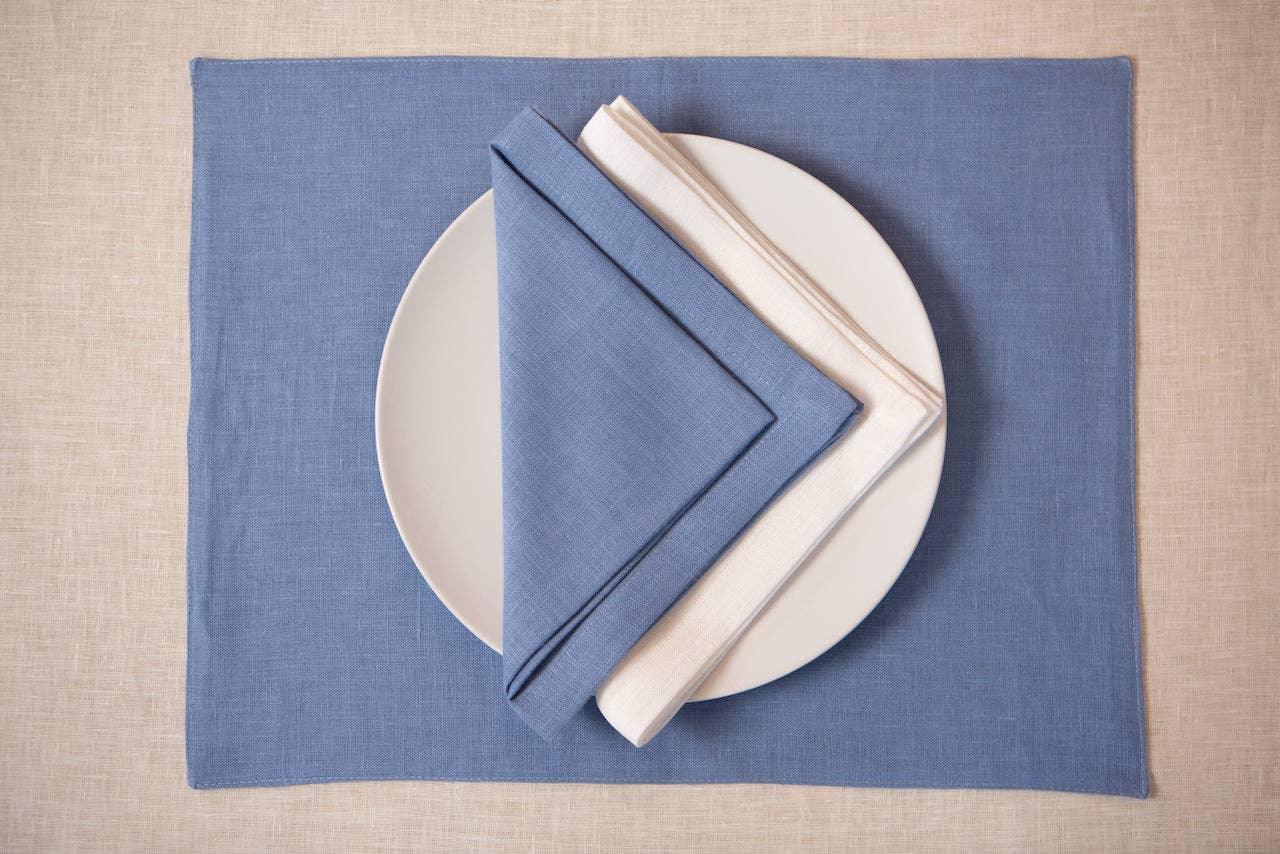 LinenCasa blue and white linen napkins on a white plate, blue placemat, neutral background