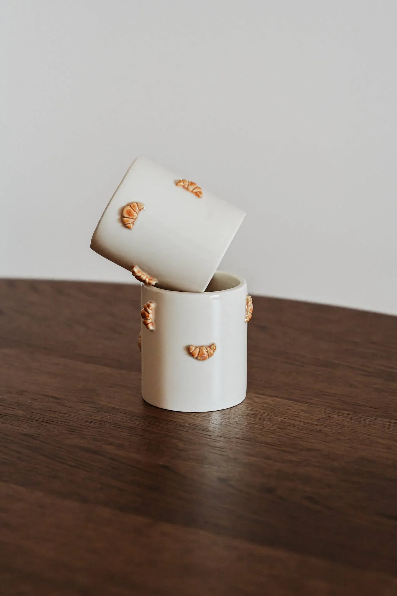 Egg Back Home white ceramic mugs with croissant details on wooden table