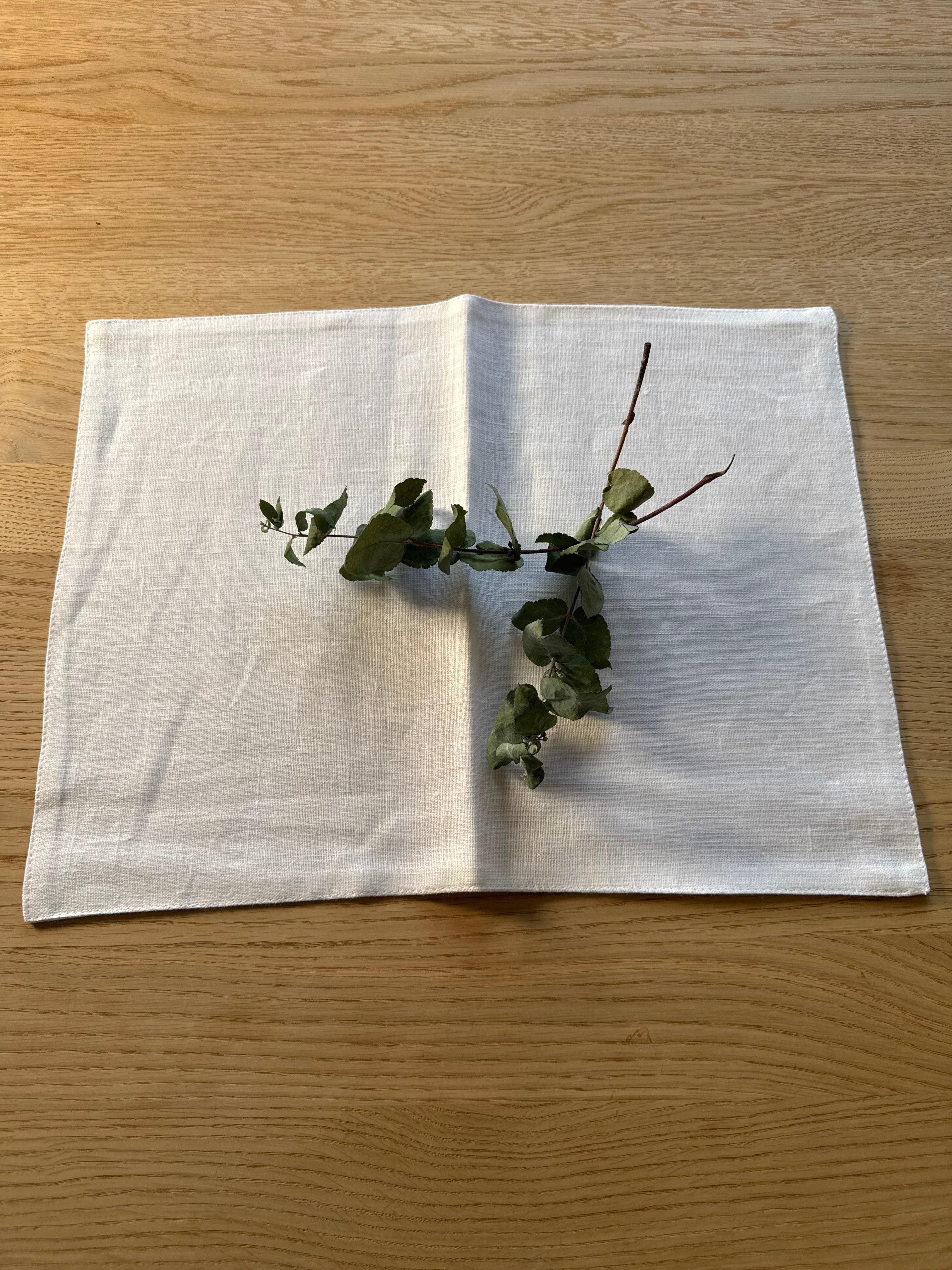 Kiroku white linen placemat with green foliage on light wood table