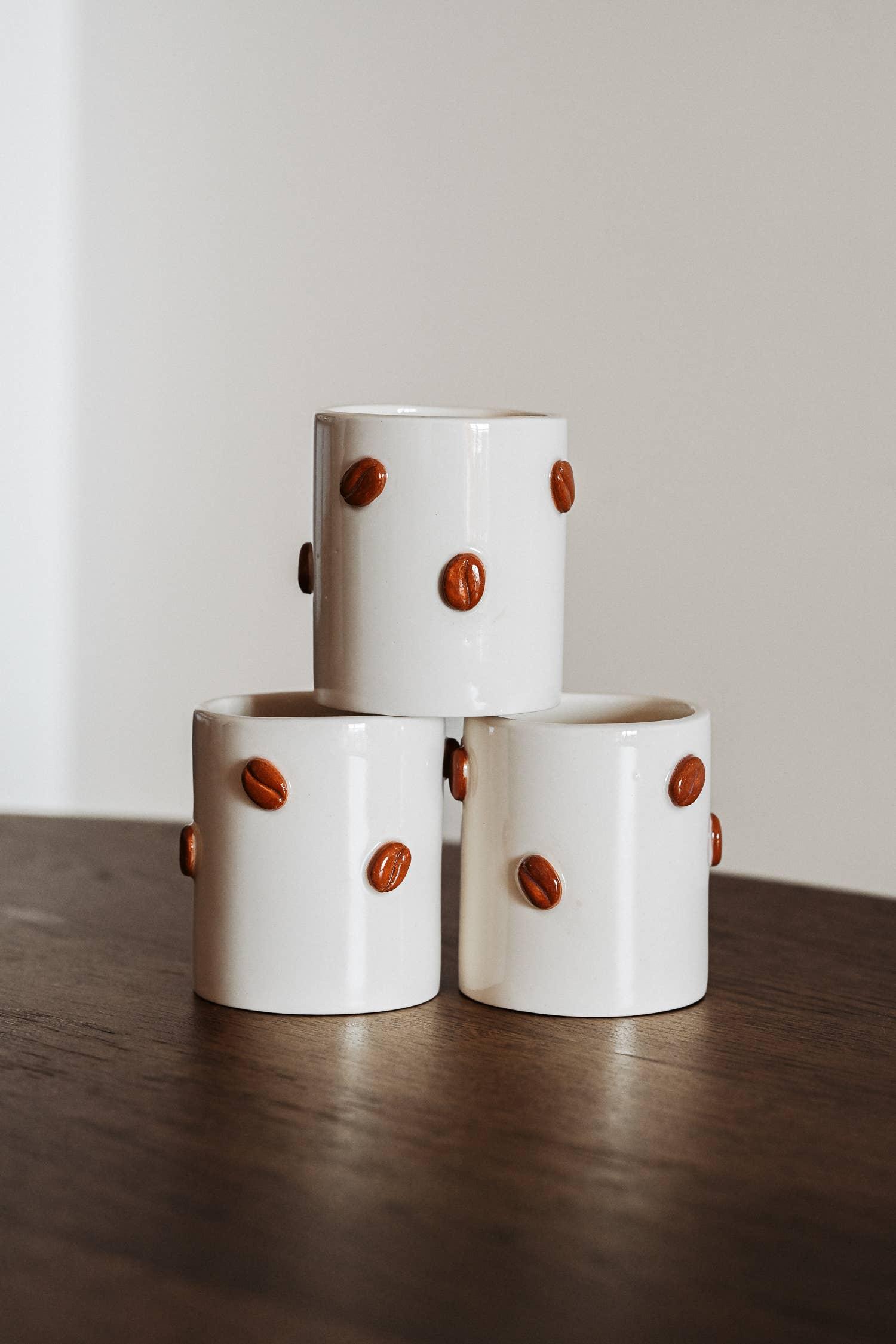 Le Petit Cloud ceramic coffee mugs with brown coffee bean accents, white finish, stacked on table