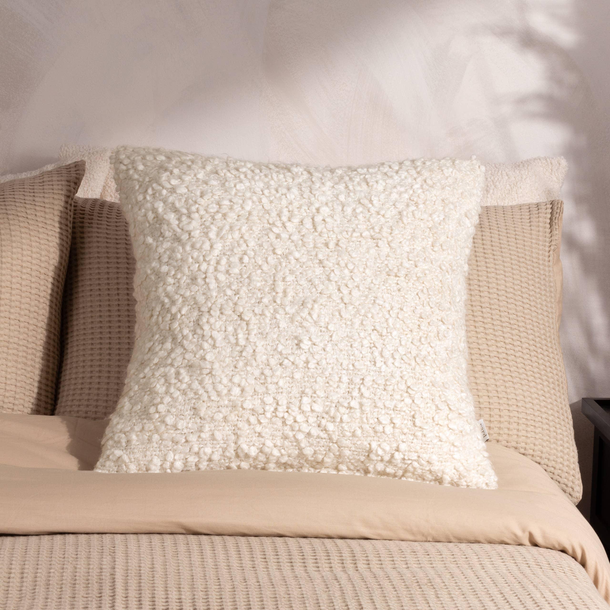 OUI boucle ivory decorative pillow on beige textured bedding, premium home decor accent