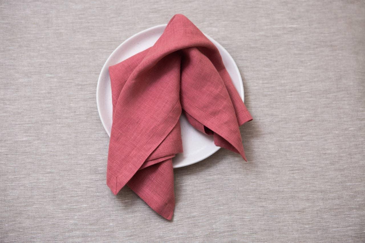 Maison Flaneur linen napkin in rose pink on a white ceramic plate, beige linen tablecloth