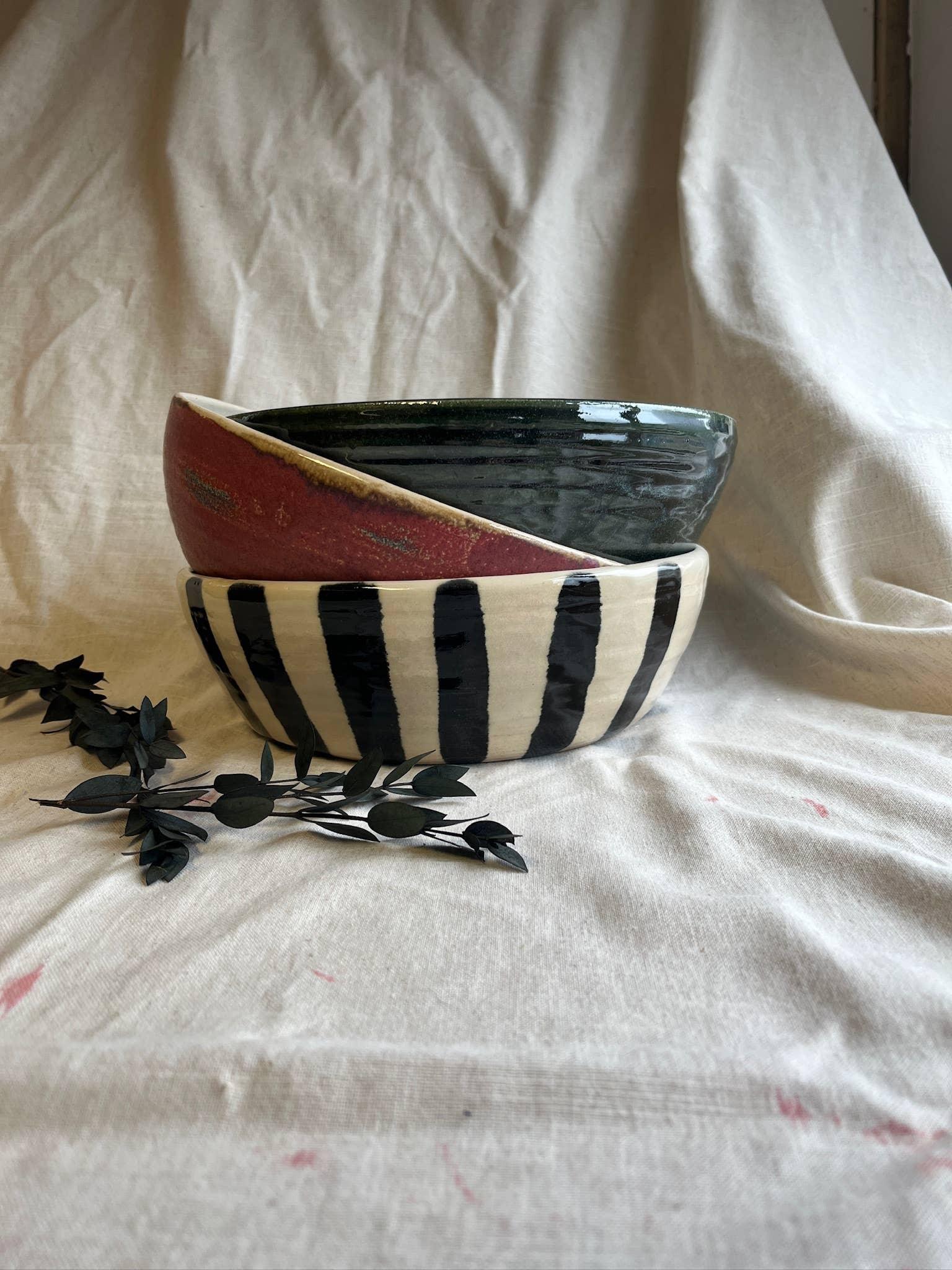 Xenia Taler ceramic bowls, hand-painted, striped black and white, and red with dark green, on fabric backdrop