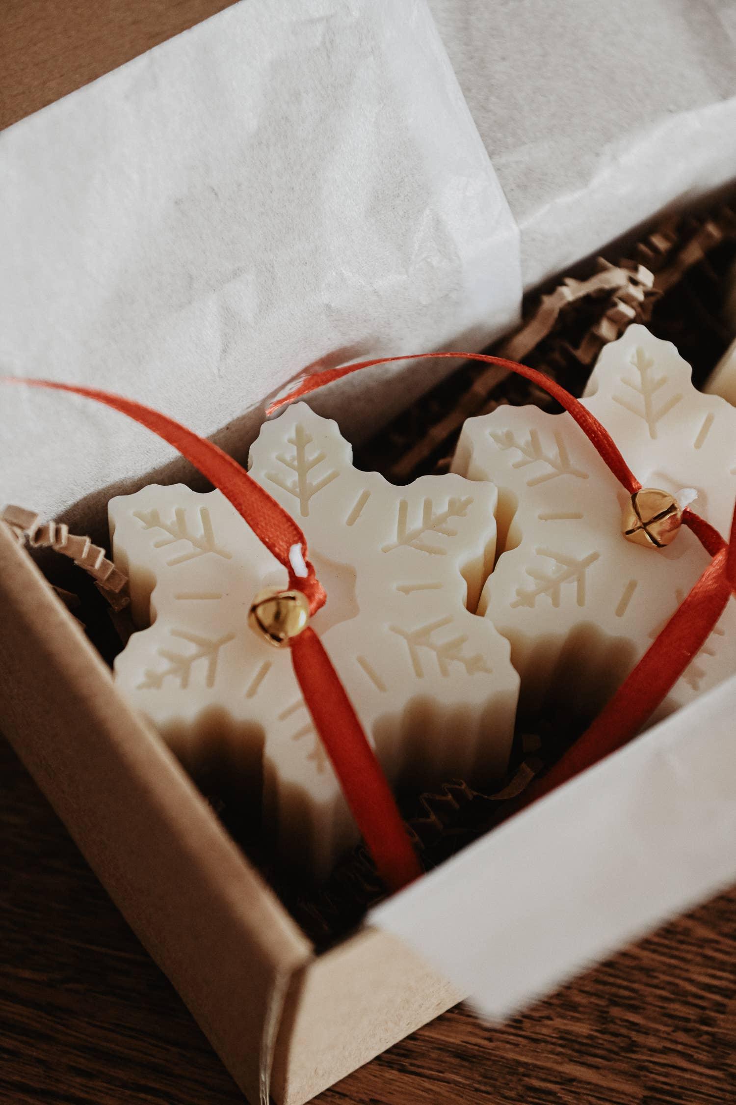 Snowflake soy wax ornaments with red ribbon and gold bell in gift box