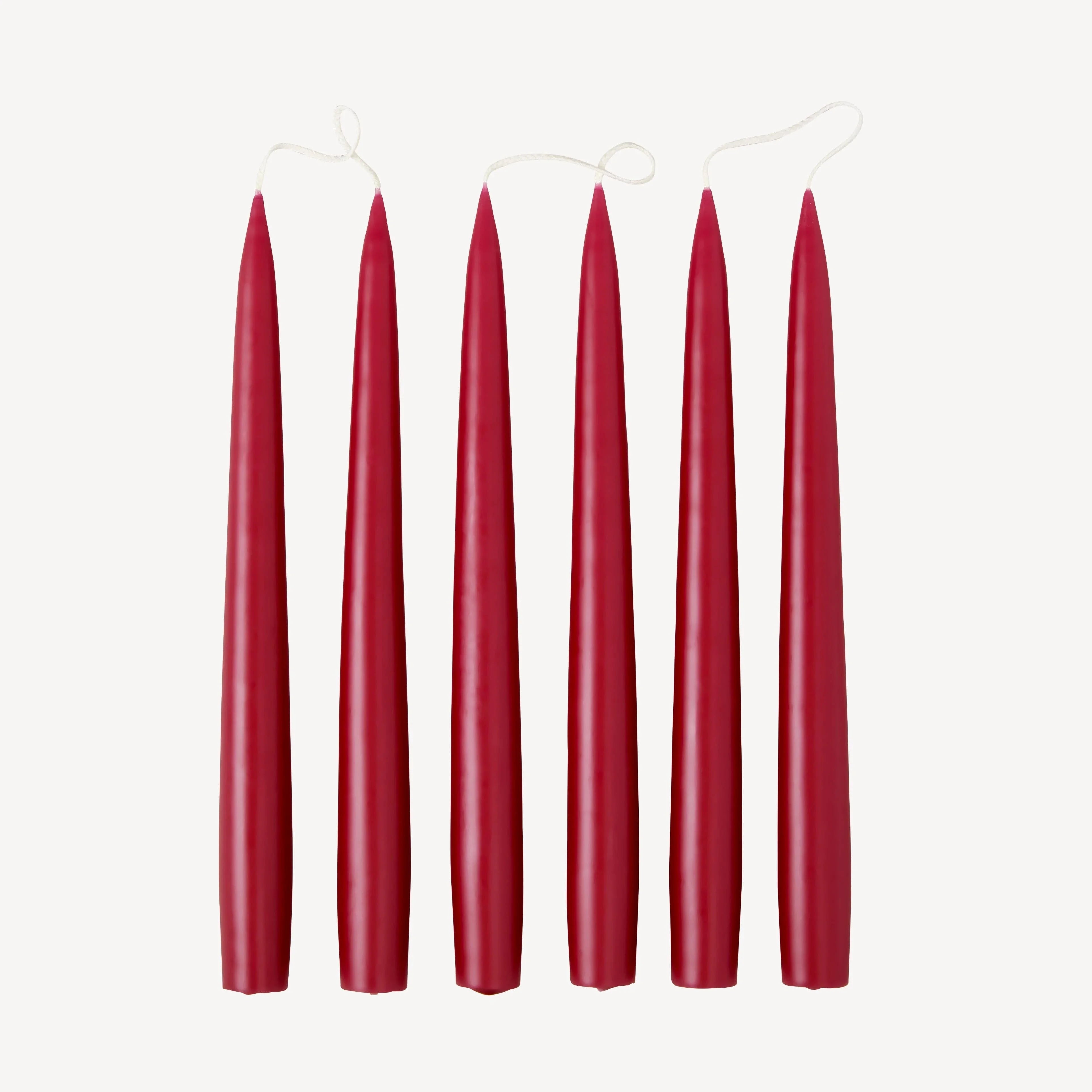 Ferm Living red wax taper candles set of five with cotton wicks on white background.