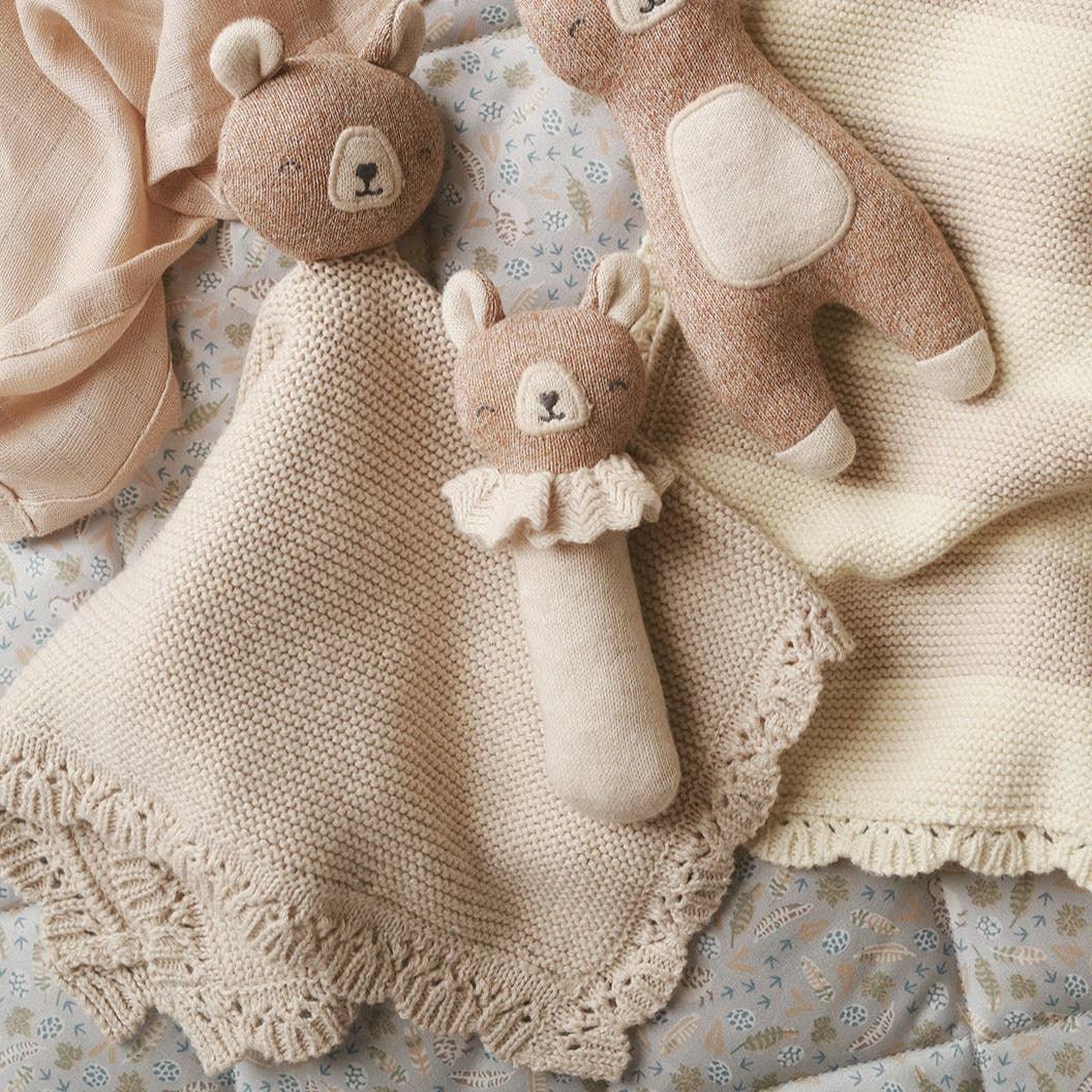 Main Sauvage knitted bear comforter and rattle, organic cotton, beige and brown, on blanket