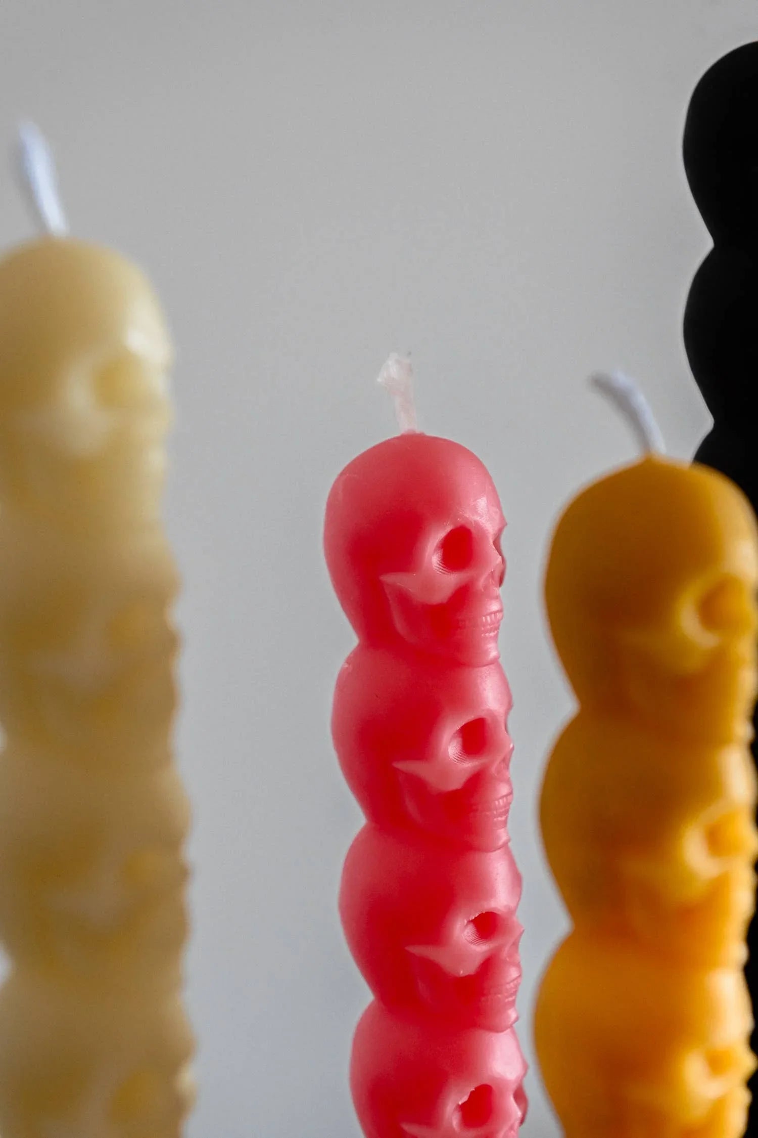 Lex Pott skull candles in pink, cream, yellow and black premium wax, close-up view