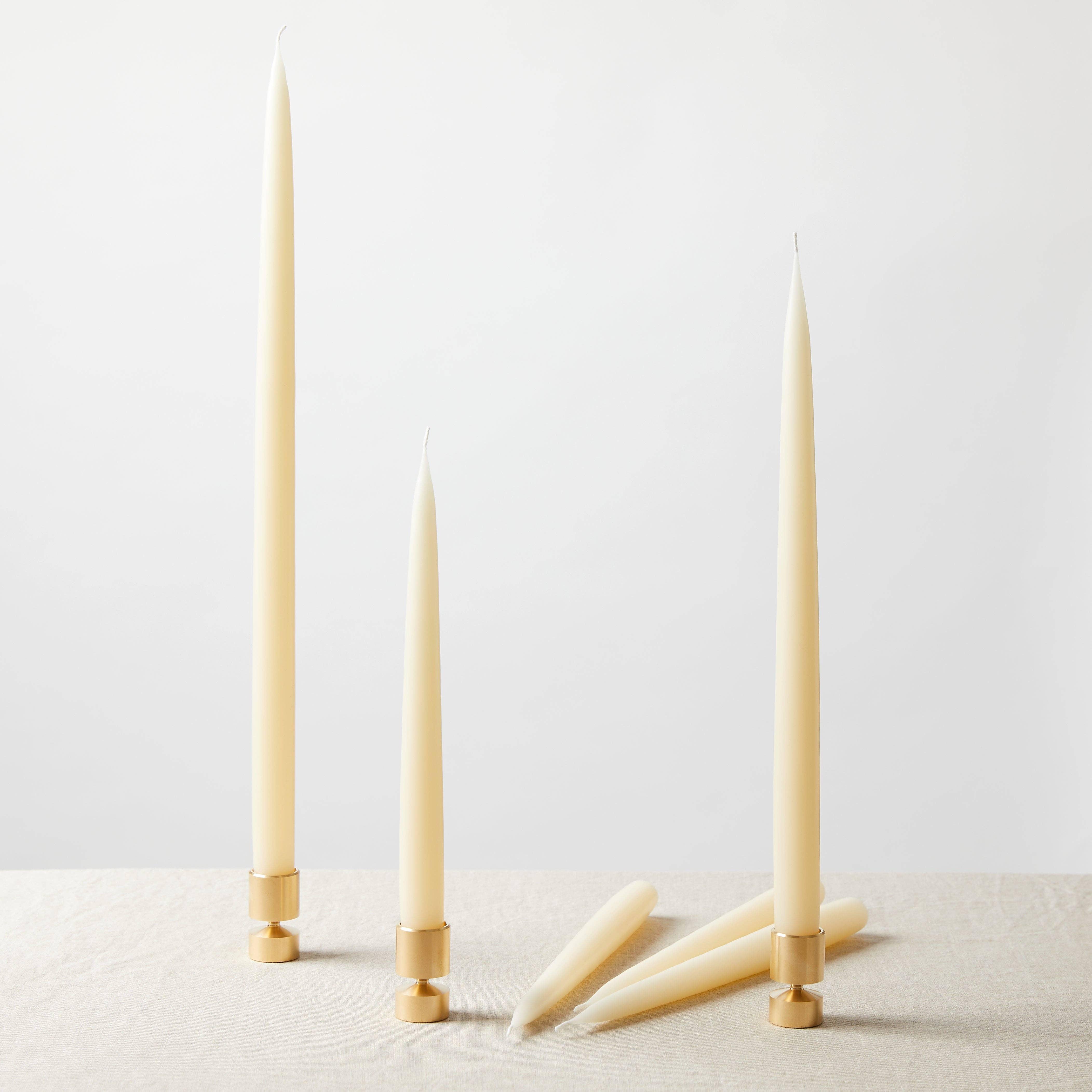 Honey Candles ivory beeswax taper candles with gold holders on neutral linen table