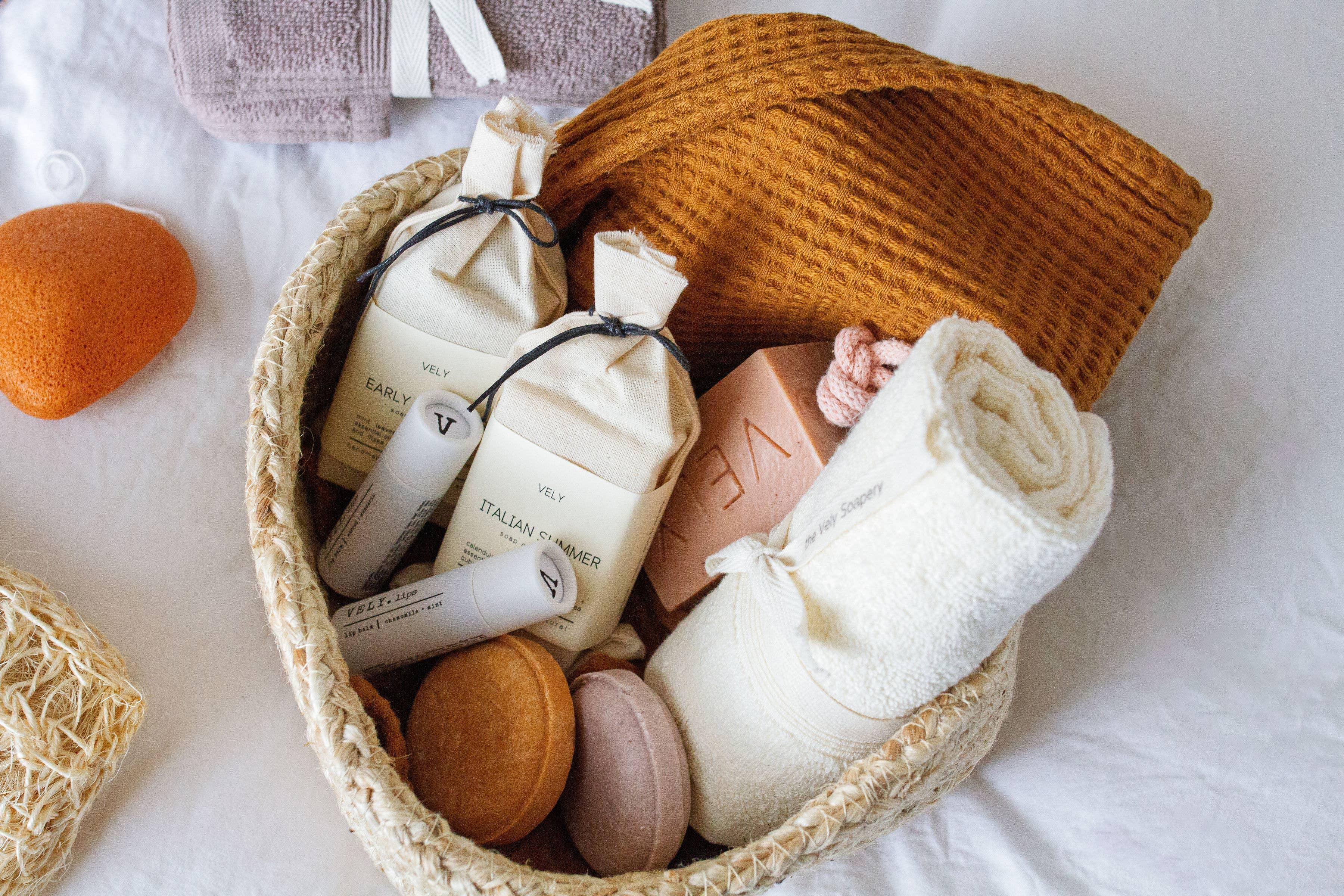 VELY spa gift basket with cotton towels, natural soaps, lip balm, and textured sponge in neutral tones