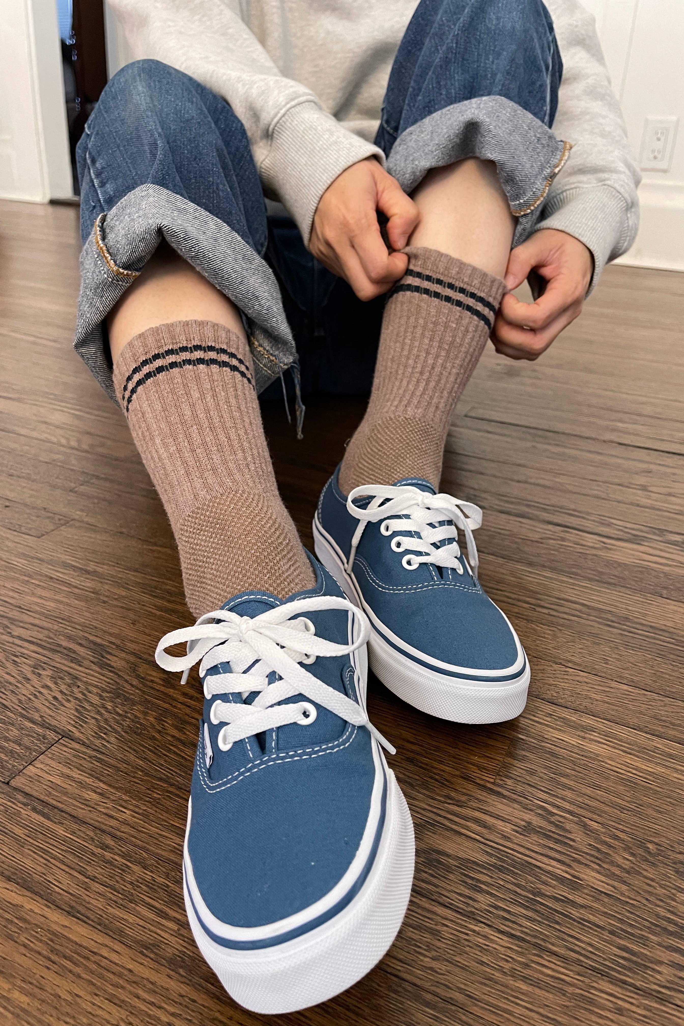 VANS blue canvas sneakers with white laces, worn with brown ribbed socks, on wood floor.