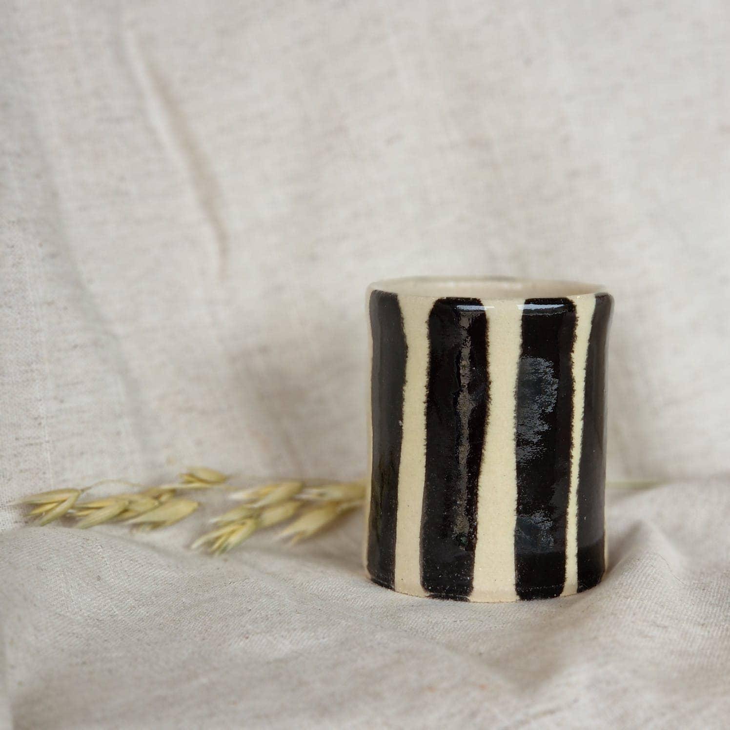 Studio Mae black and cream ceramic tumbler with vertical stripes on linen backdrop