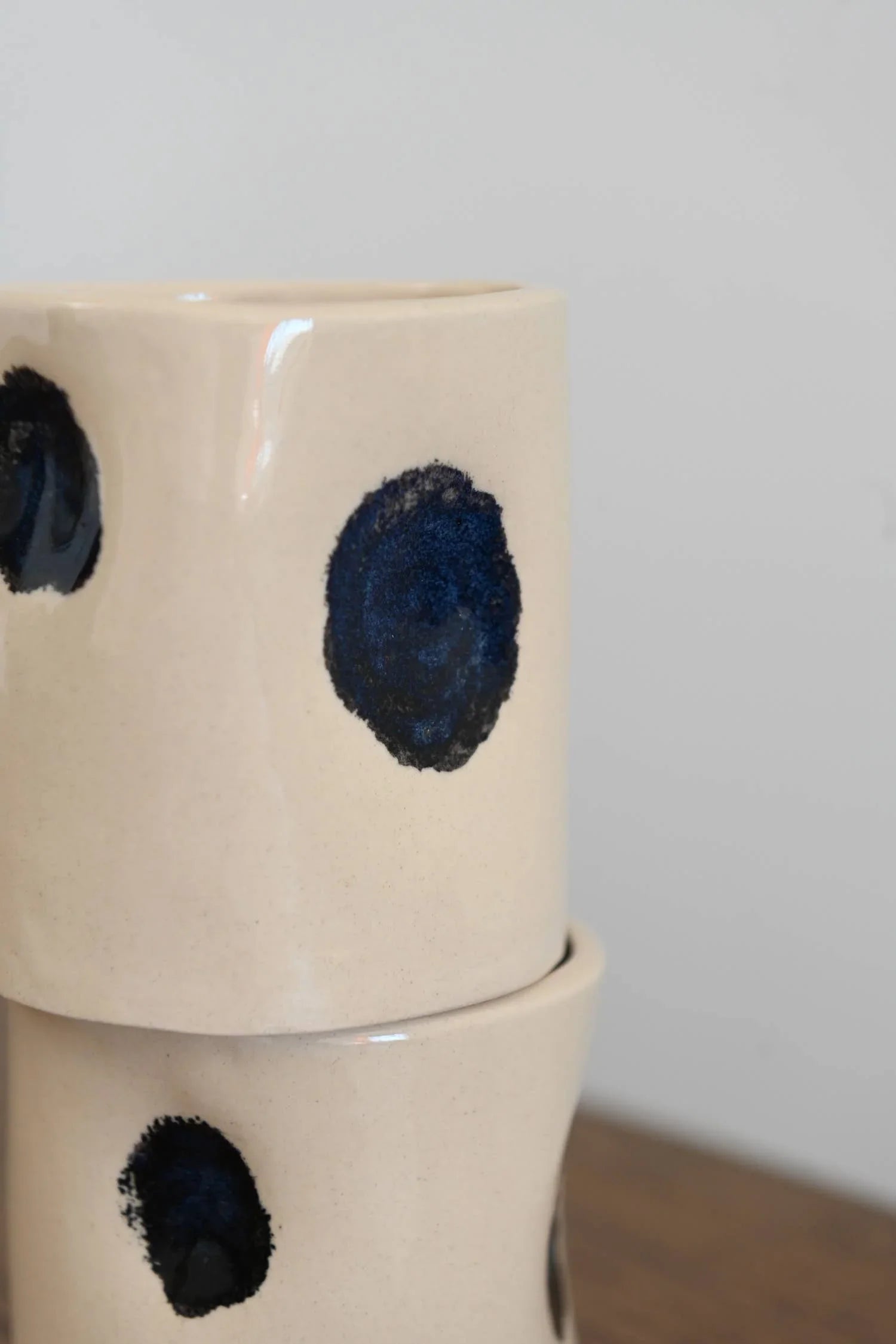 Rachael Pots ceramic mugs in cream with blue dot pattern, stacked on wood surface