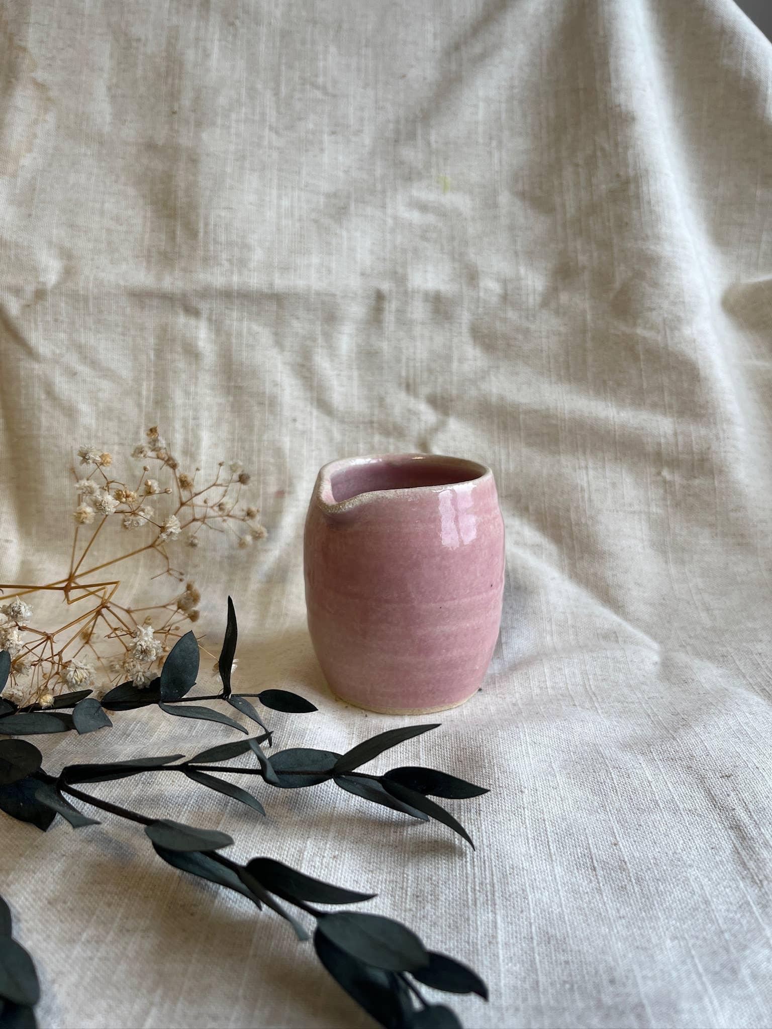 Handcrafted pink ceramic vase on linen fabric with dried flowers, minimal design