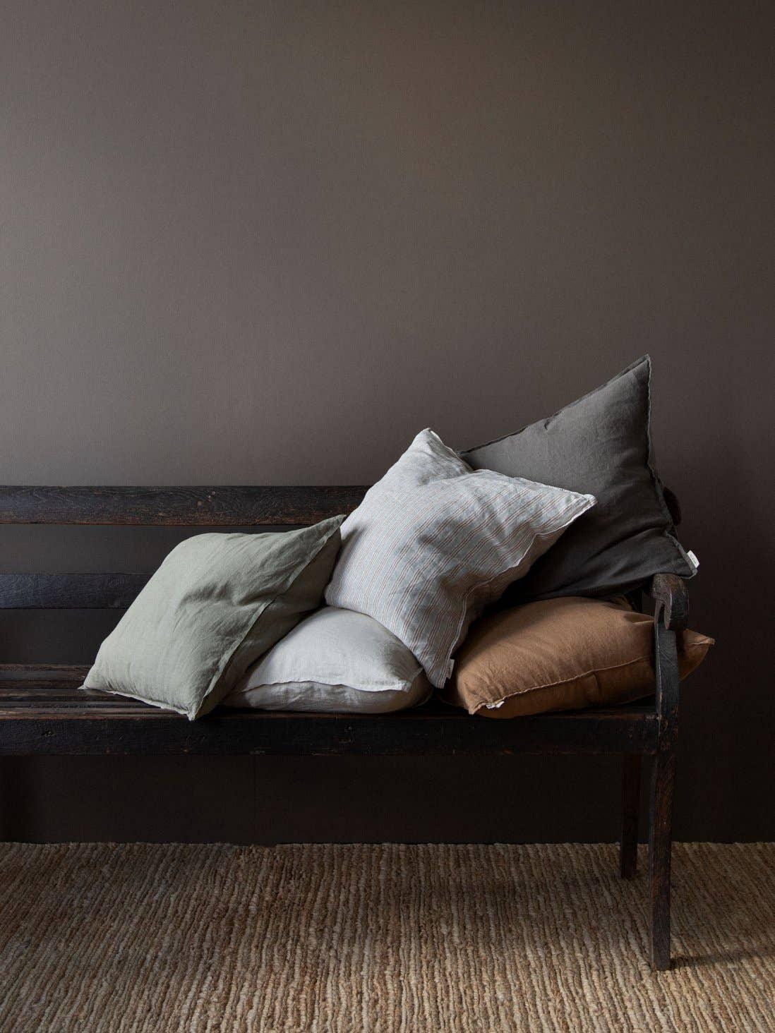 LINEN TALES linen cushion covers in grey, beige, and brown on rustic wooden bench