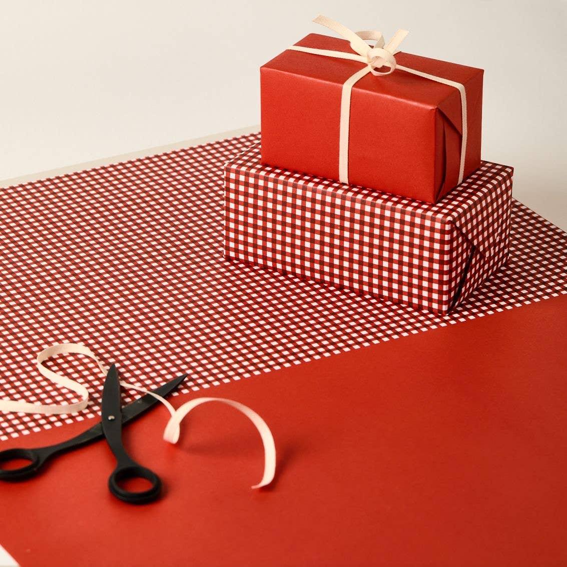 Rifle Paper Co. red and white gift wrap set with ribbon and black scissors on table