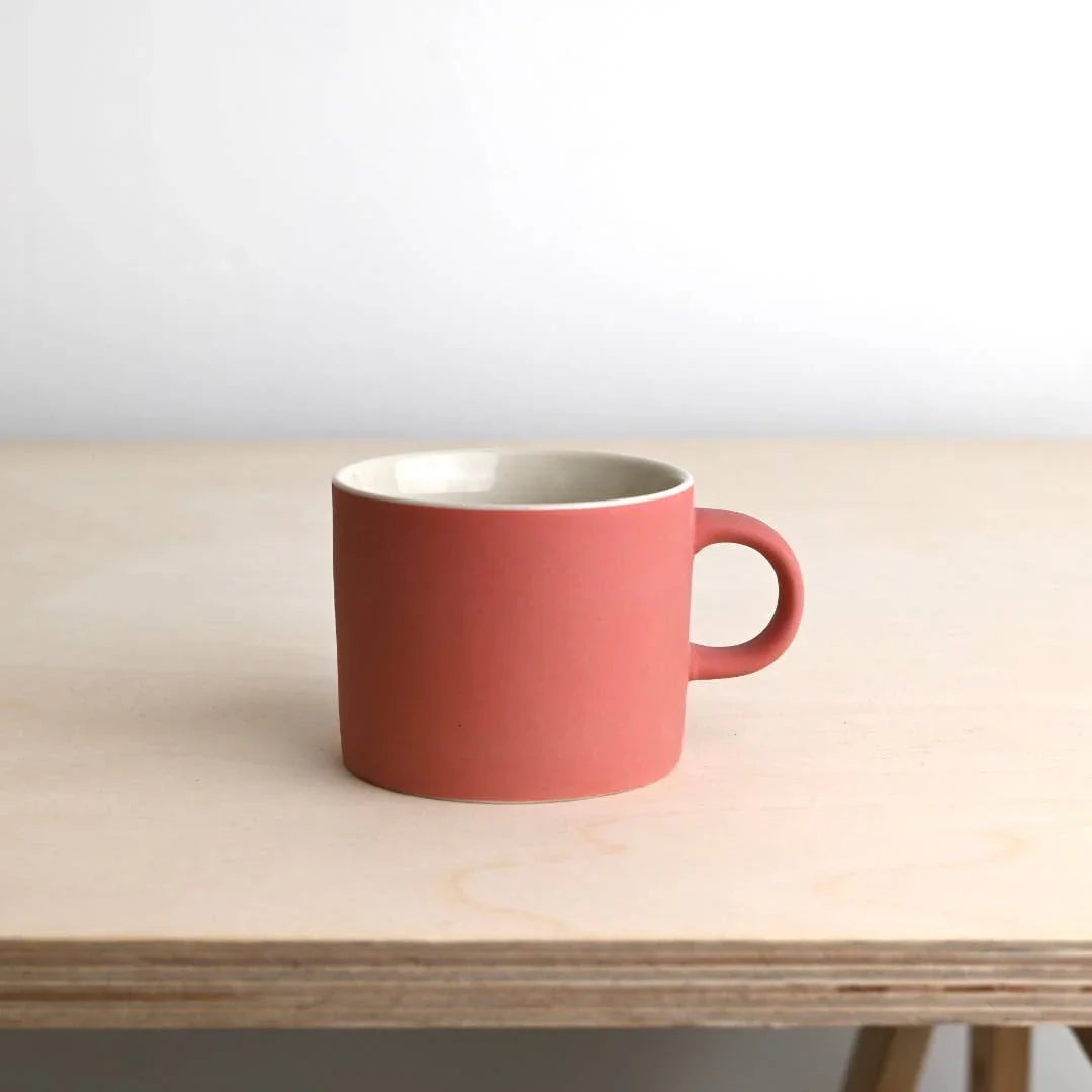 Hasami Porcelain ceramic mug in matte pink, minimalist Japanese design on wooden table