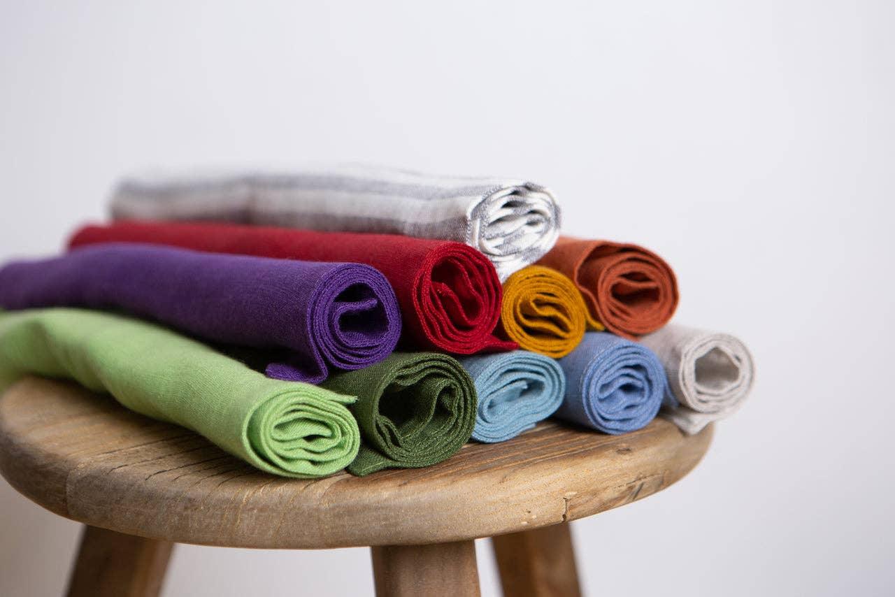 MERCE hand-rolled cotton napkins in assorted colors on a wooden stool