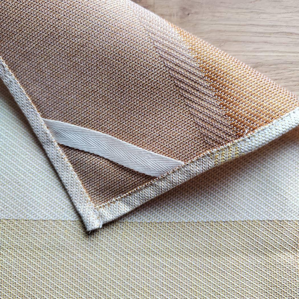 Pace Linen tea towel in beige and cream cotton-linen blend on wood surface