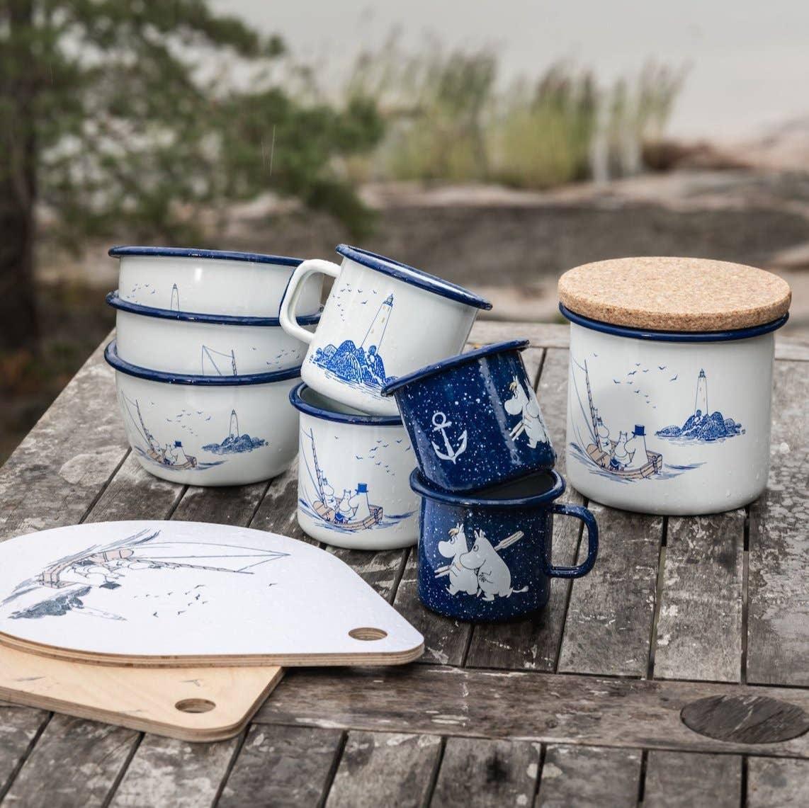 Muurla Moomin enamel mugs, bowls, and container in blue and white on rustic wood table