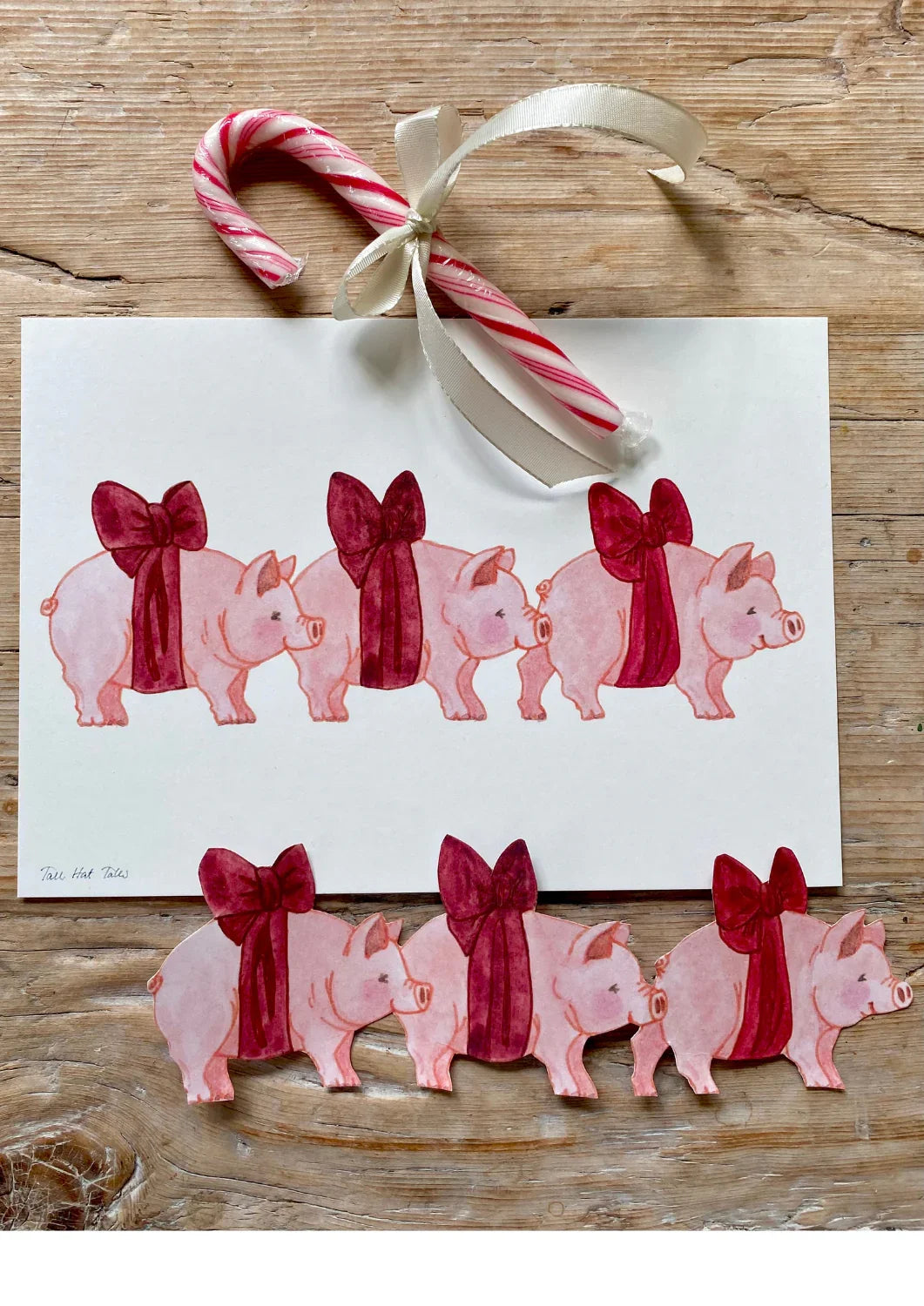 Tail Hat Tales holiday card with pink pigs in red bows on premium paper, candy cane accessory