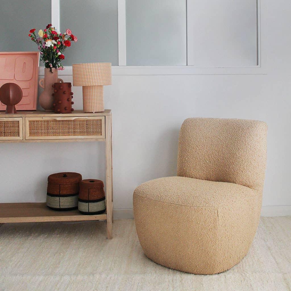 The French Viking cream boucle accent chair in a modern living room with rattan console and decor