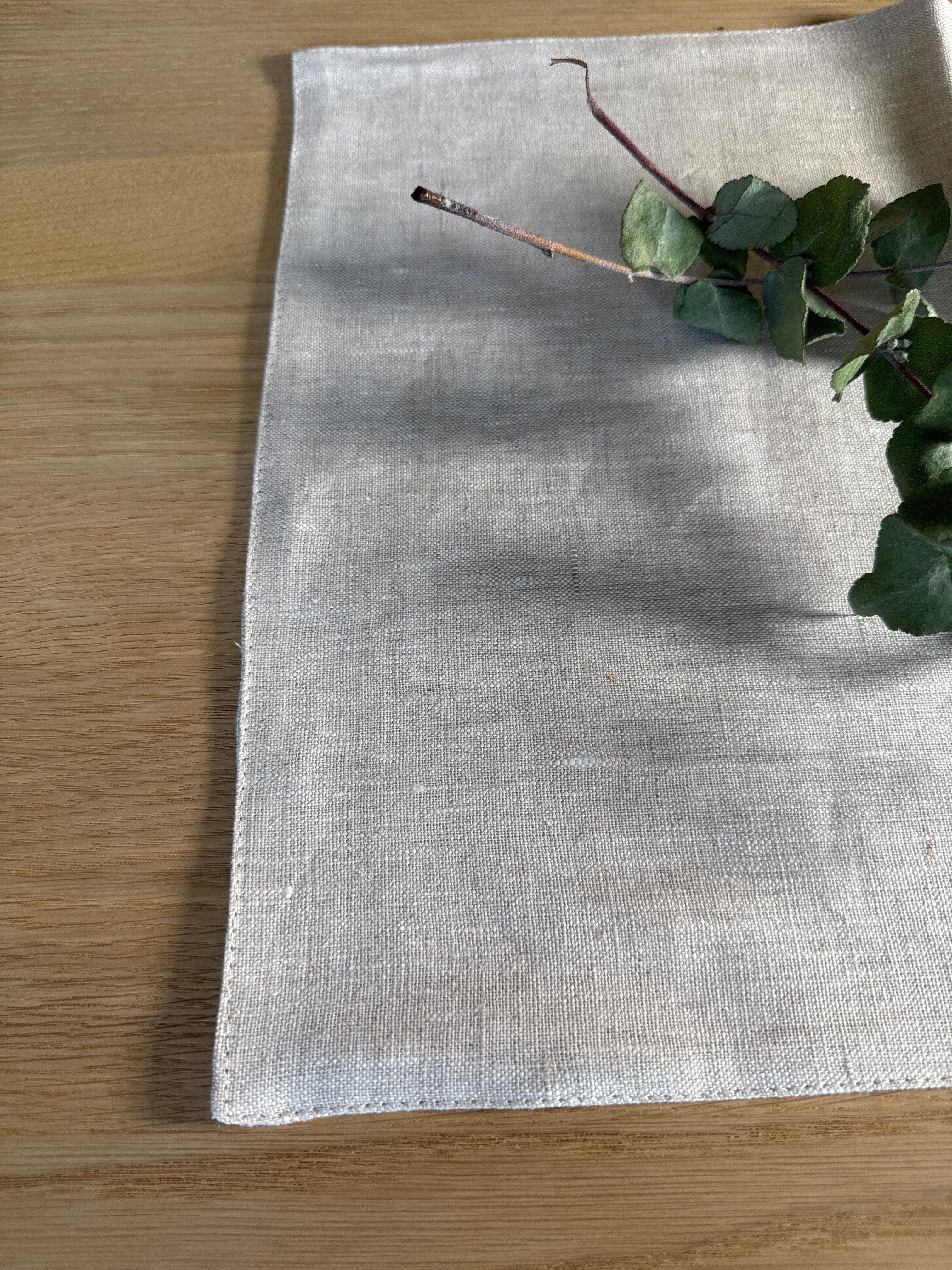 INU linen placemat in natural beige on wood table with eucalyptus stem