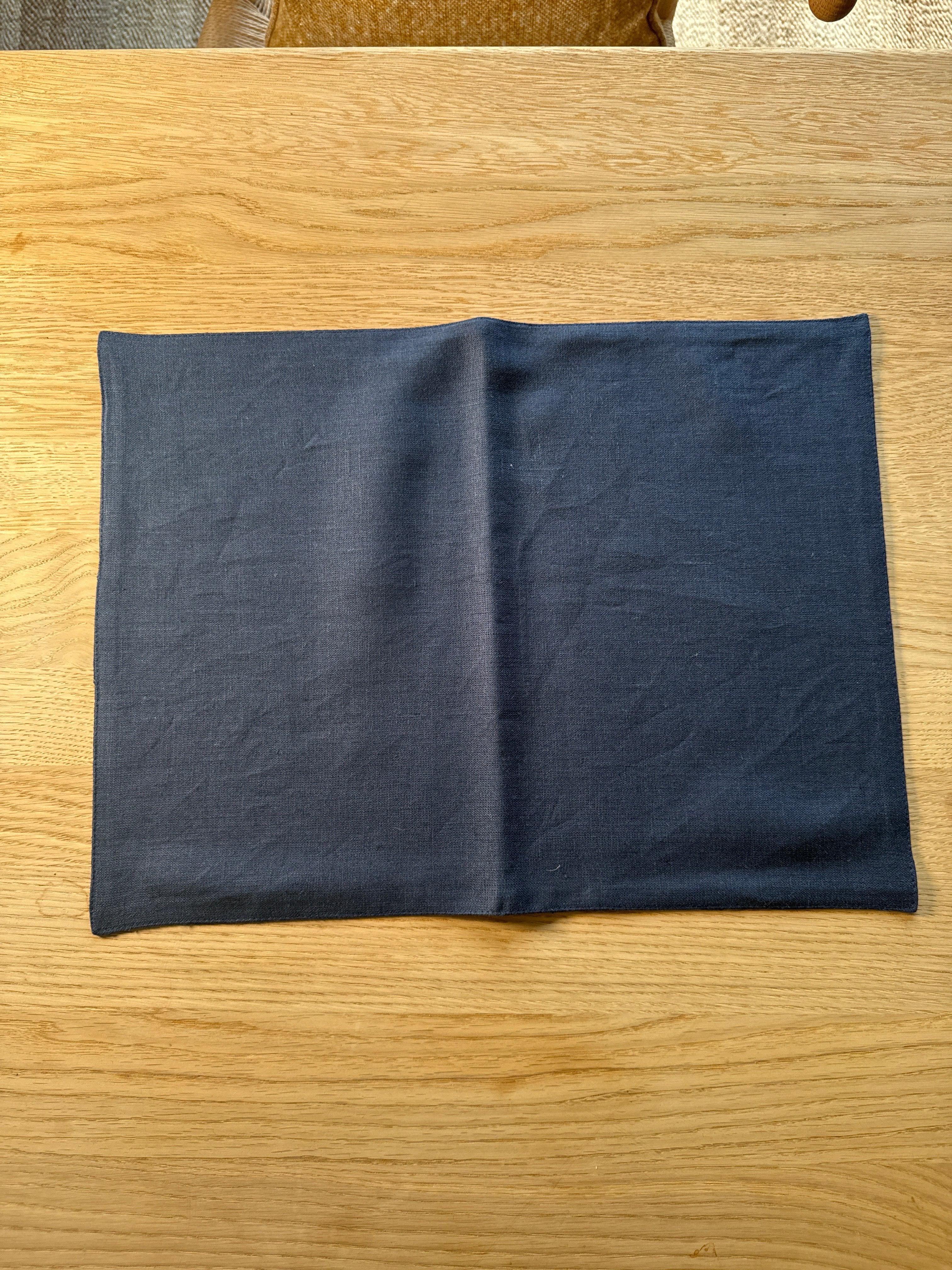 Dark linen placemat on light wood table, premium fabric, modern minimalist design