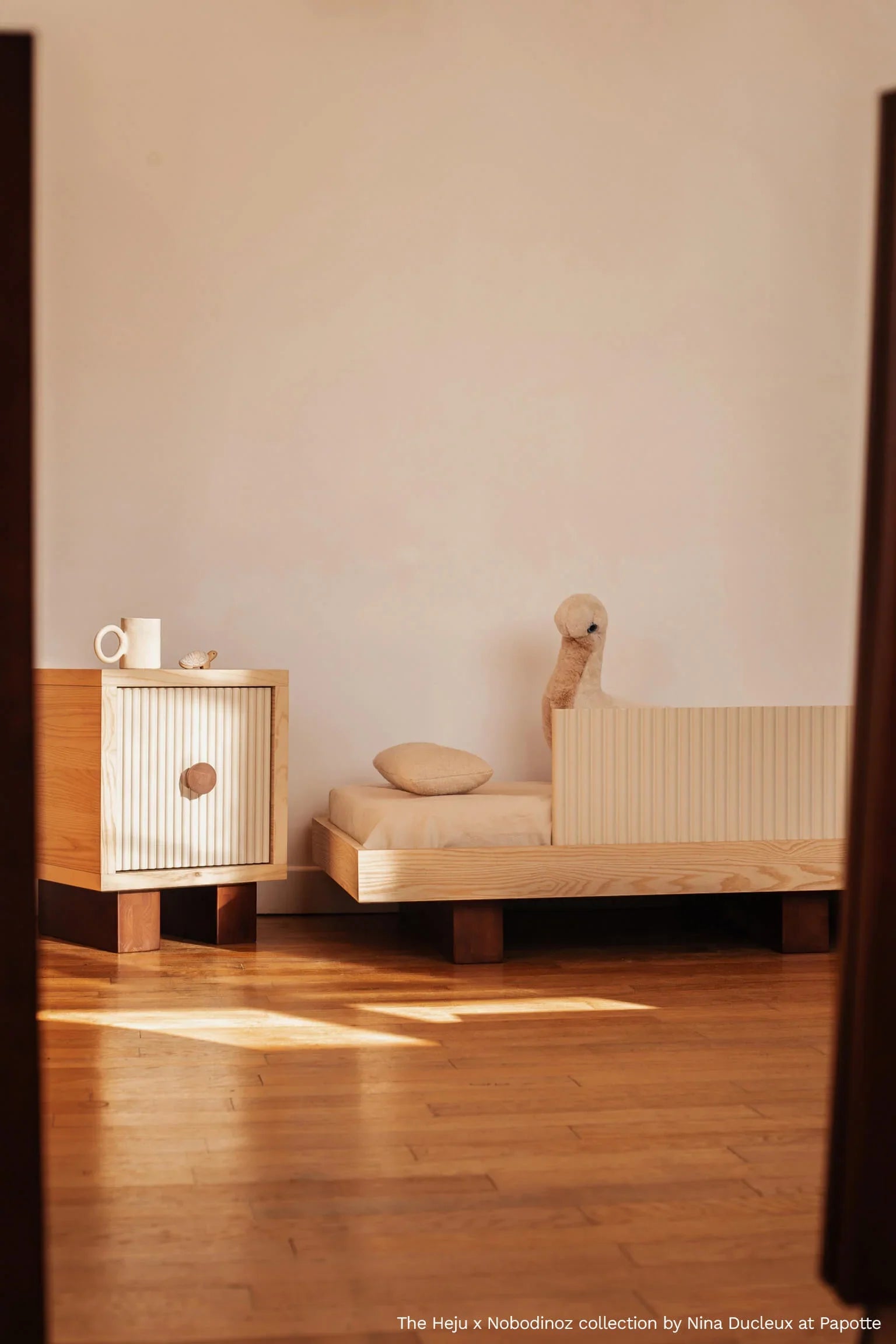 Heju x Nobodinoz wooden bedside table in light wood with ribbed door and round handle, beige setting